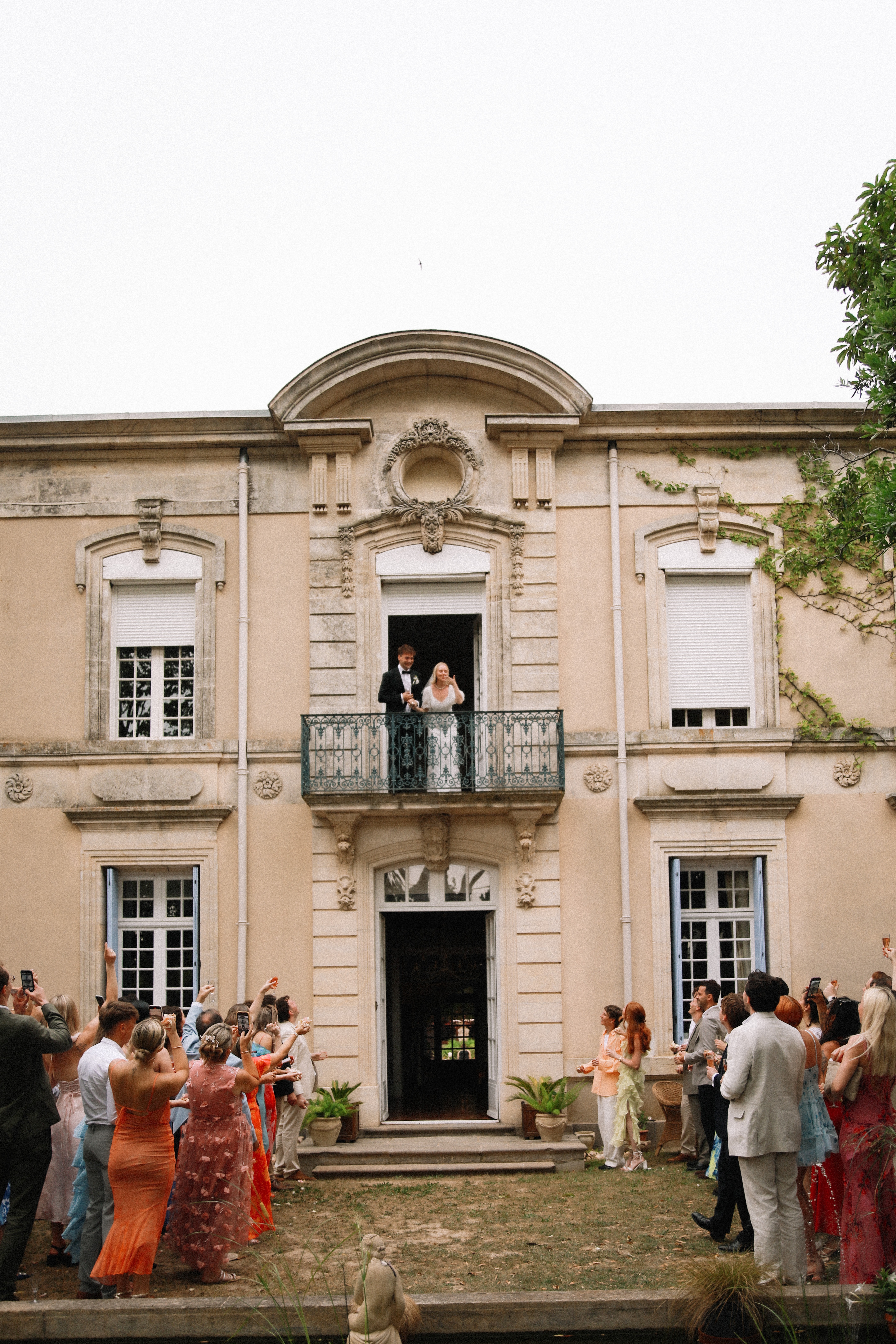 Tall view of chateau facade with balcony and guests at Chateau du Puits es Pratx, Ginestas