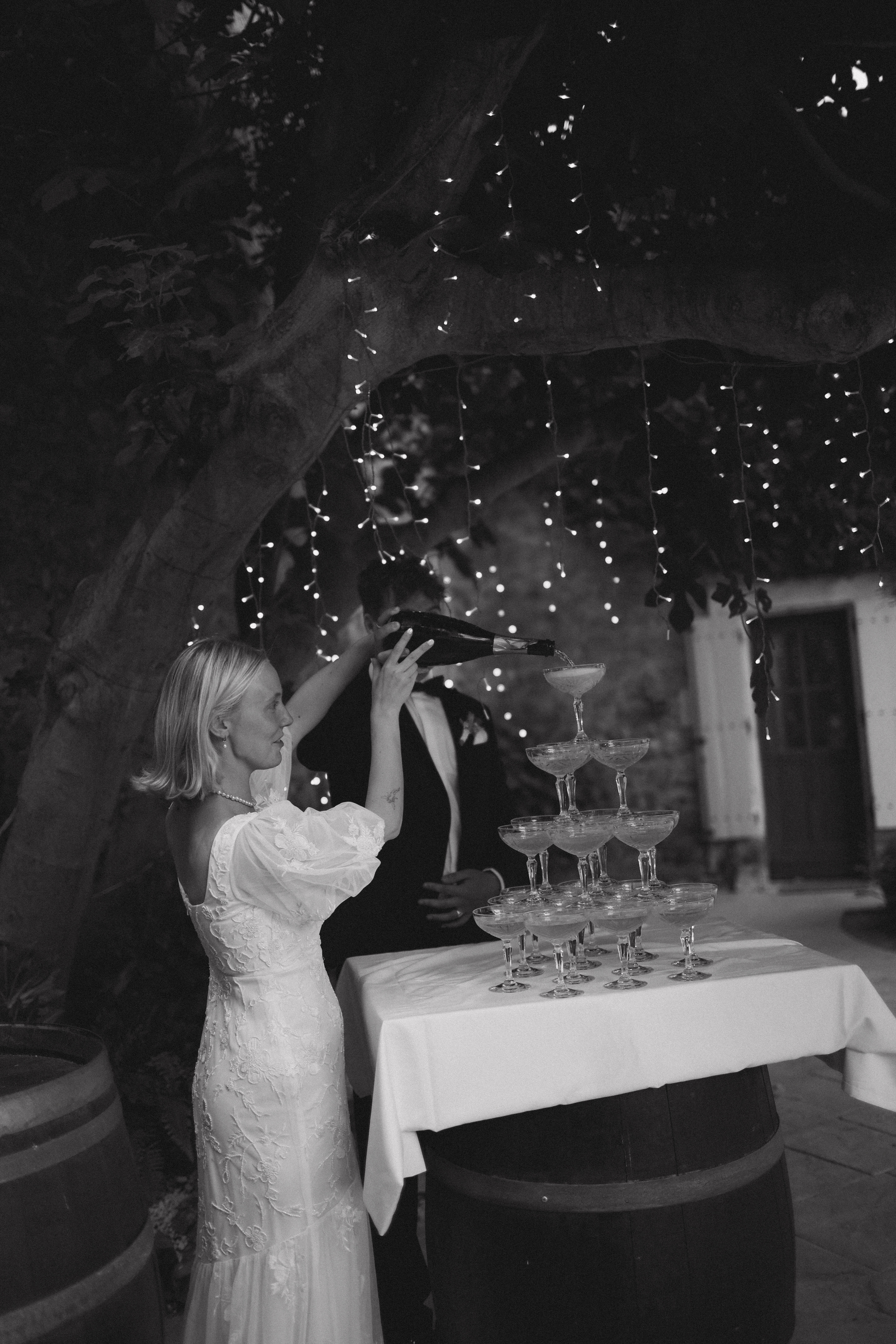 Couple pouring champagne tower in black and white at Chateau du Puits es Pratx, Ginestas