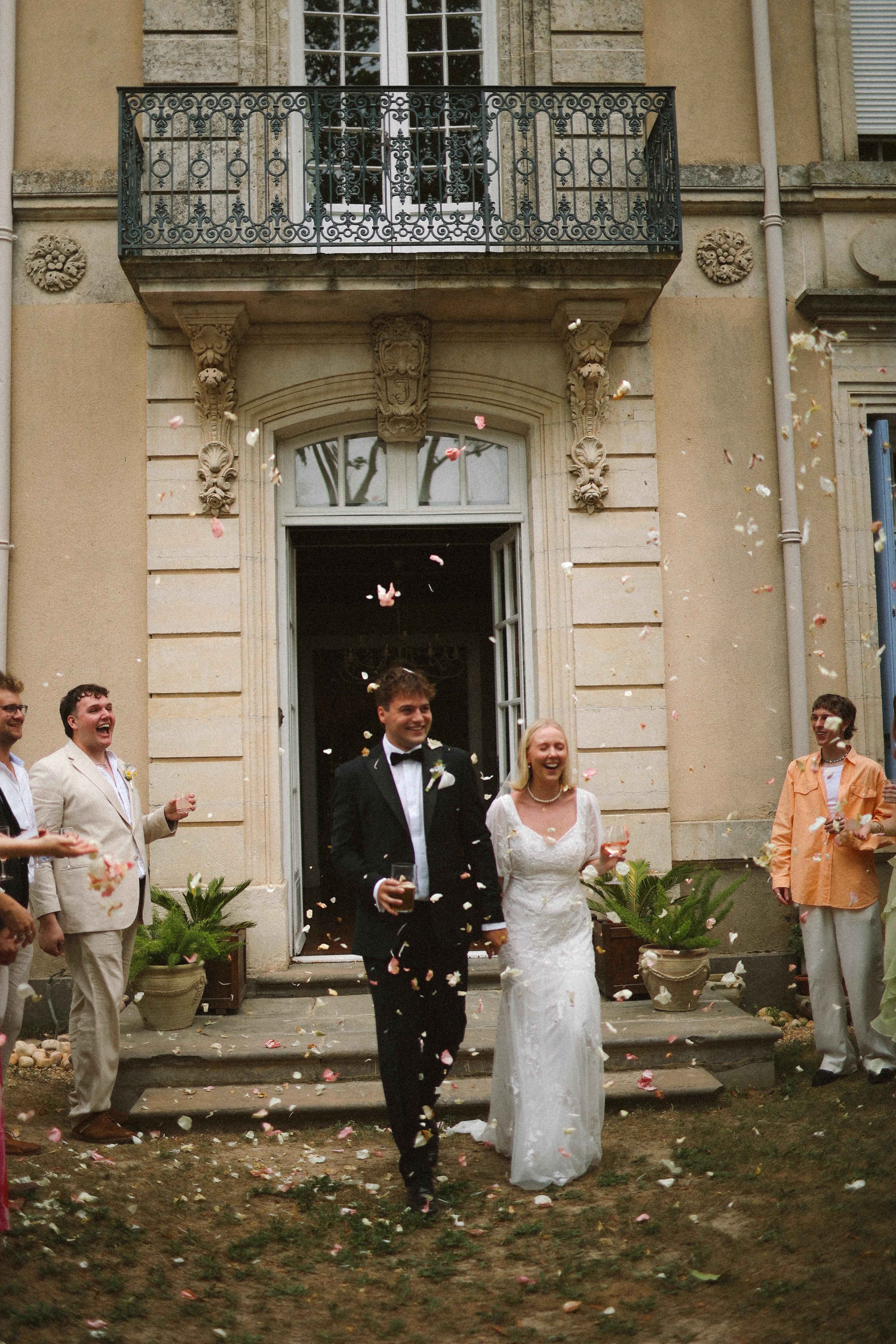 Couple exit chateau under petal toss at Chateau du Puits es Pratx, Ginestas