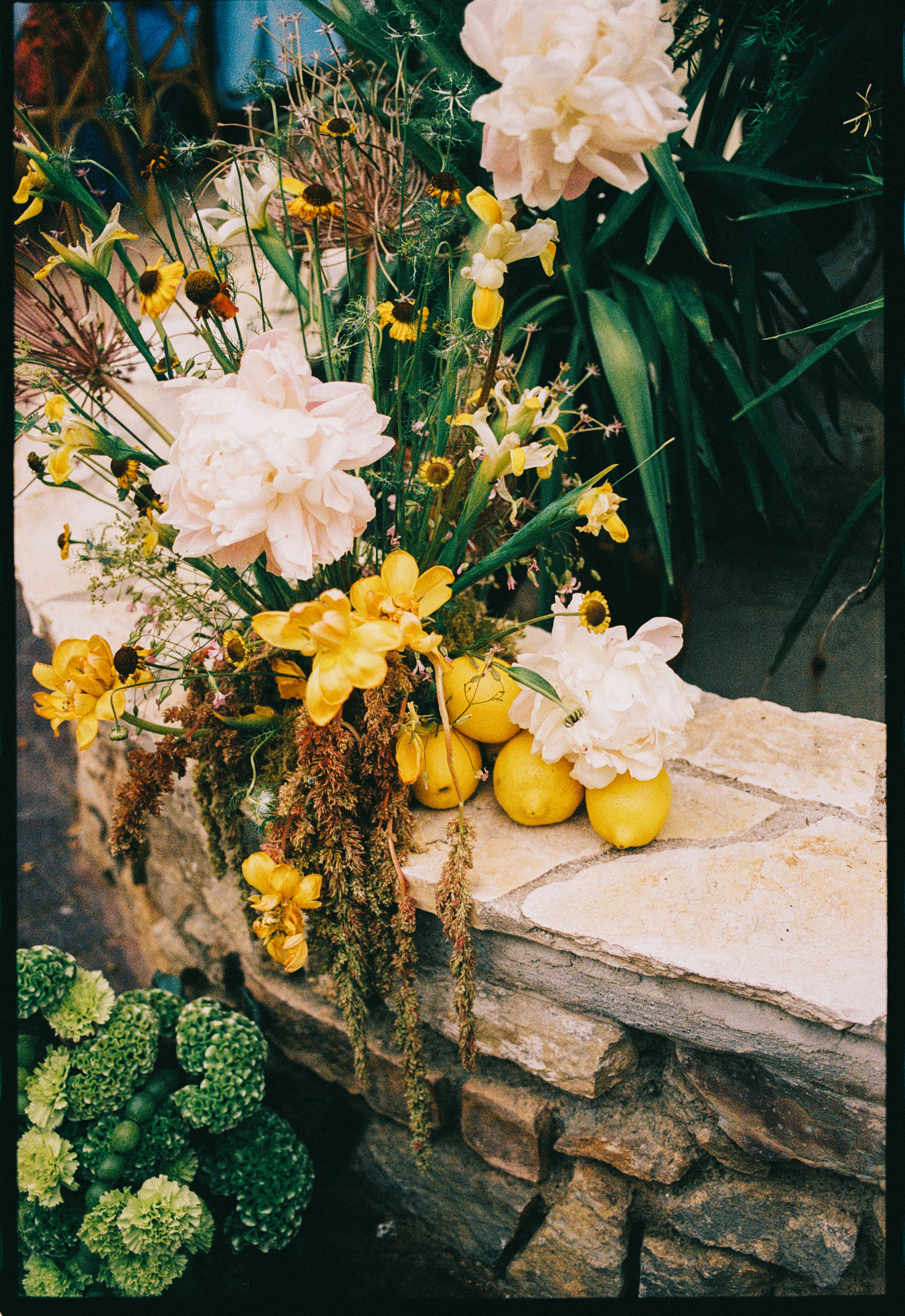 Floral arrangement with peonies and lemons on stone wall at Chateau du Puits es Pratx, Ginestas