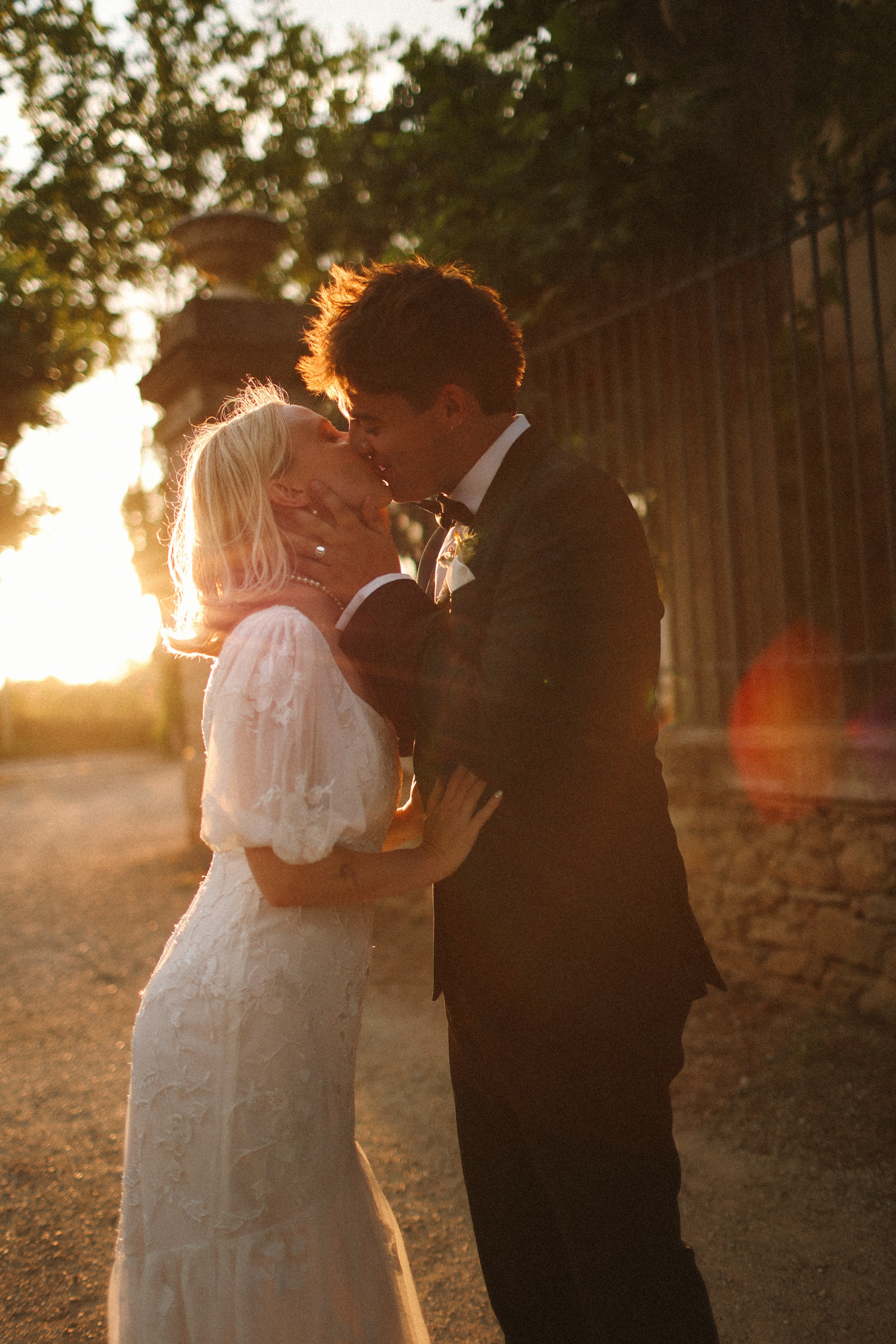 Couple kiss at golden hour with sun flare at Chateau du Puits es Pratx, Ginestas
