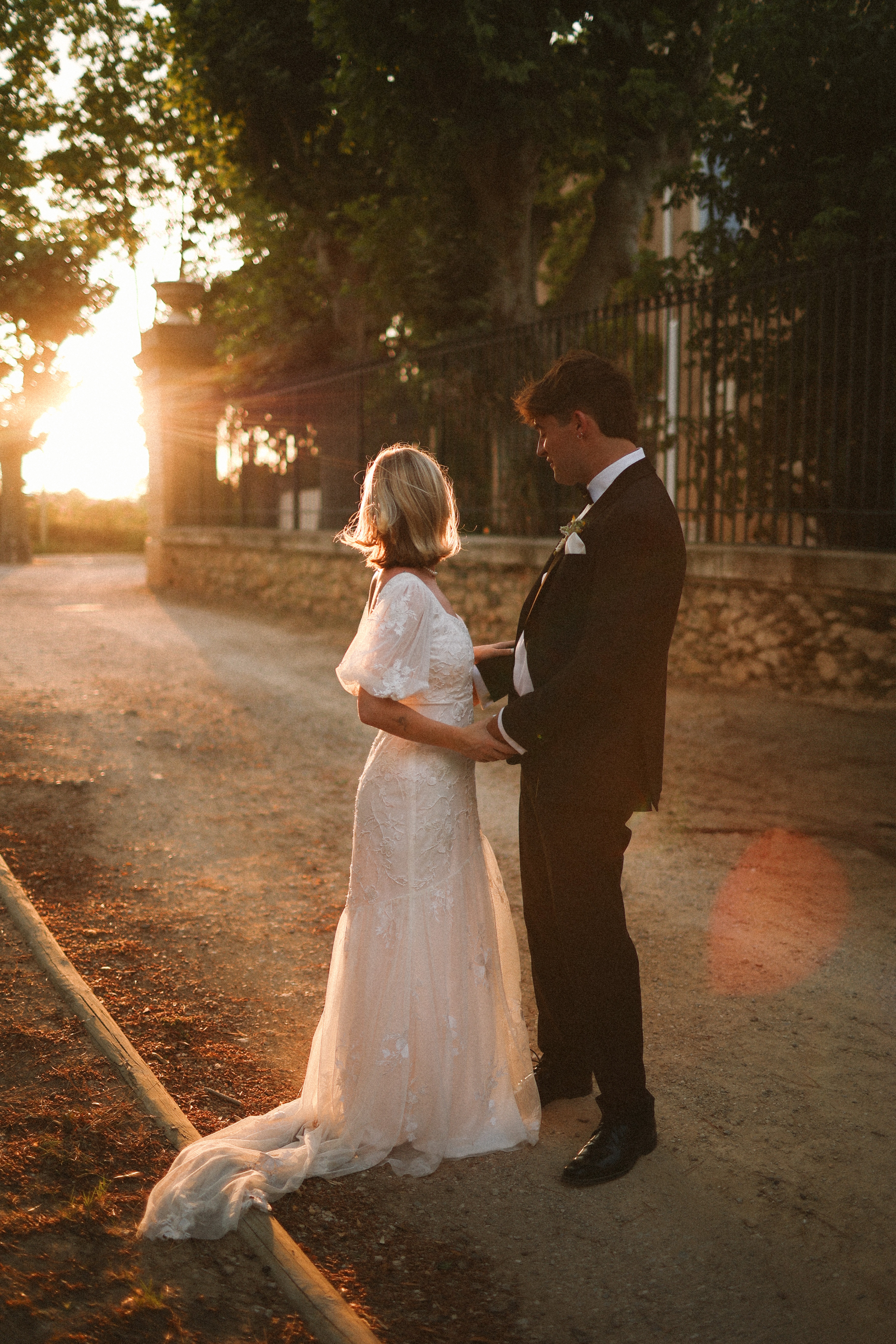 Couple embracing at golden hour on gravel path at Chateau du Puits es Pratx, Ginestas