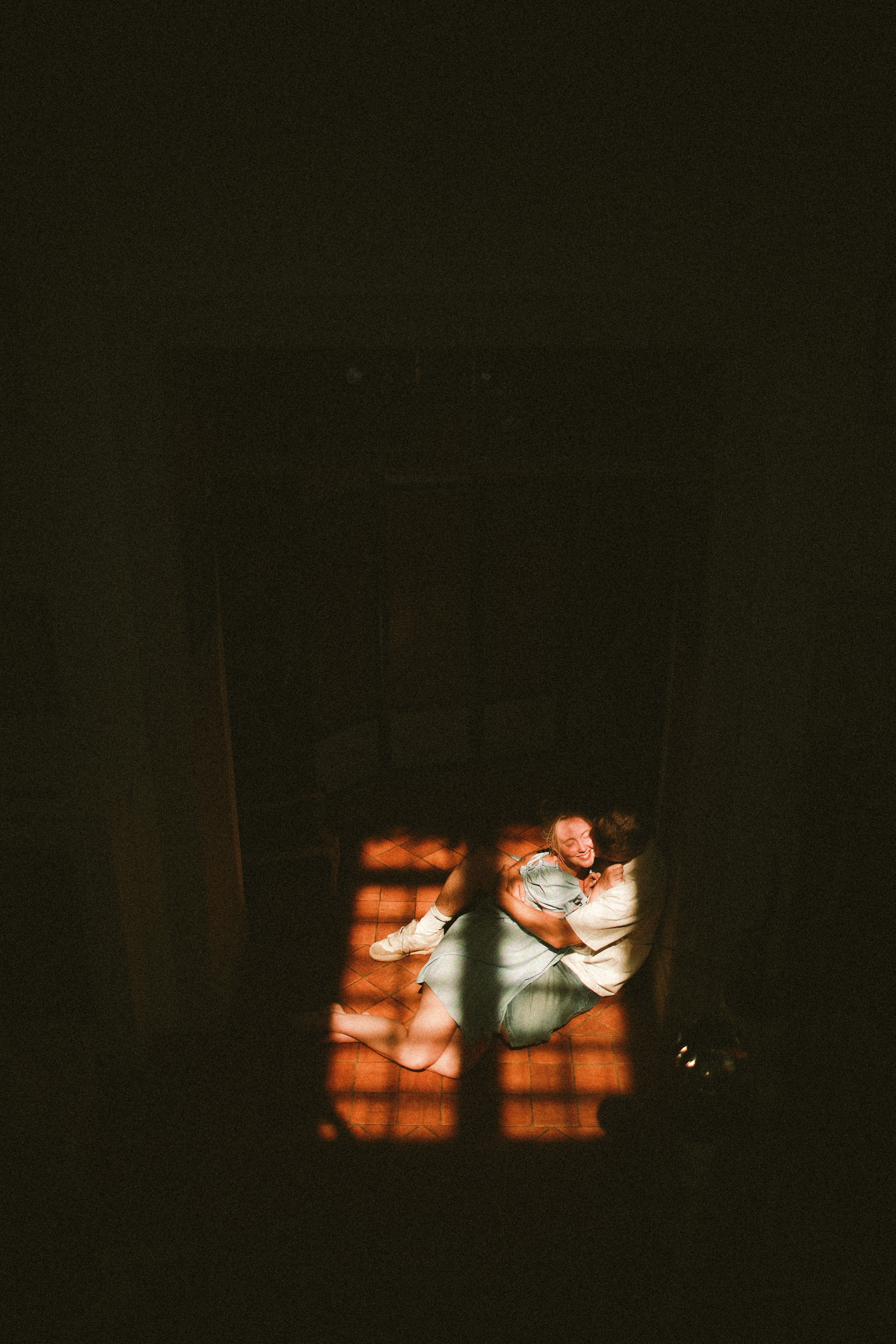 Couple embracing on tile floor in light shaft at Chateau du Puits es Pratx, Ginestas