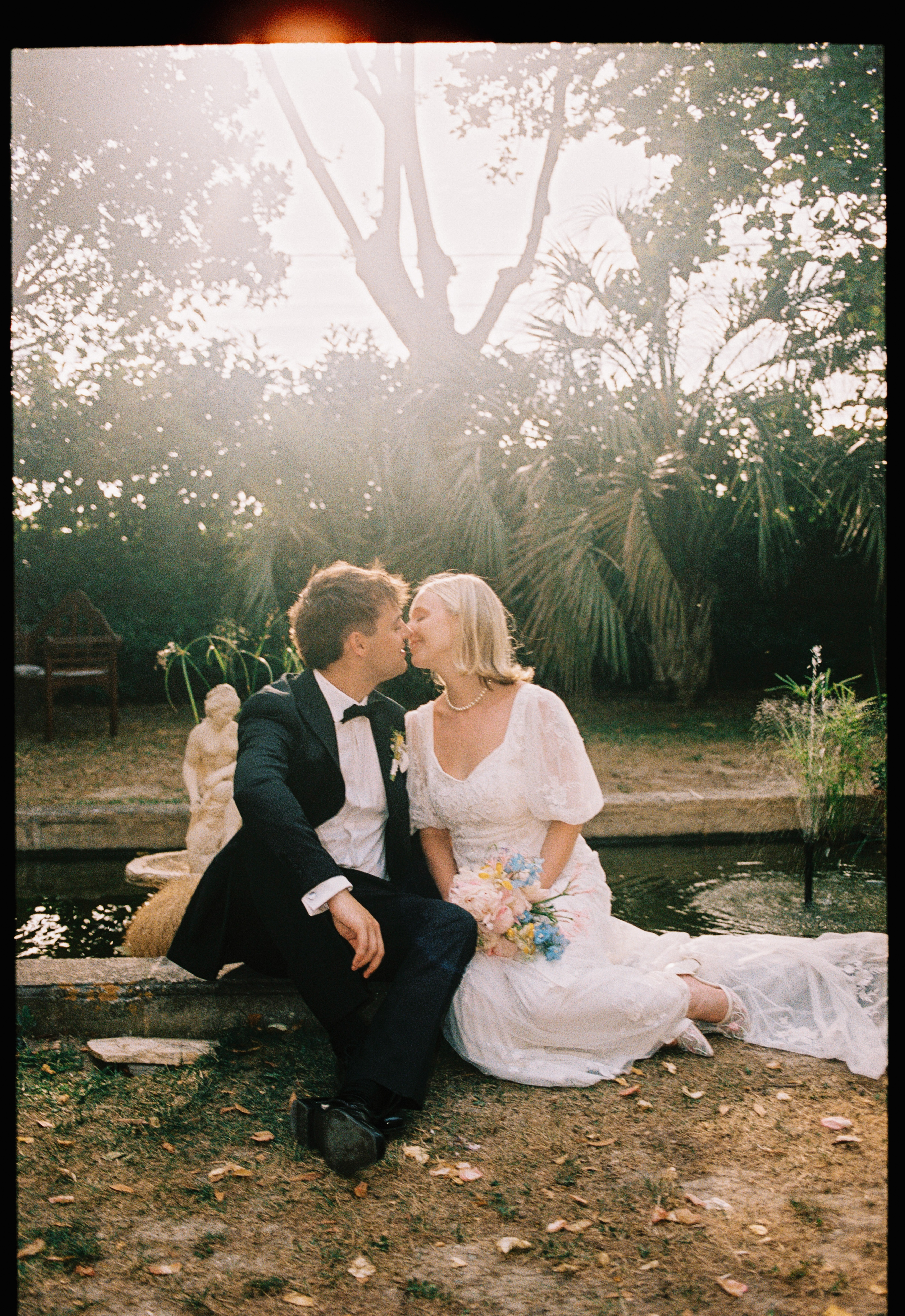 Couple kissing by garden pond at golden hour at Chateau du Puits es Pratx, Ginestas
