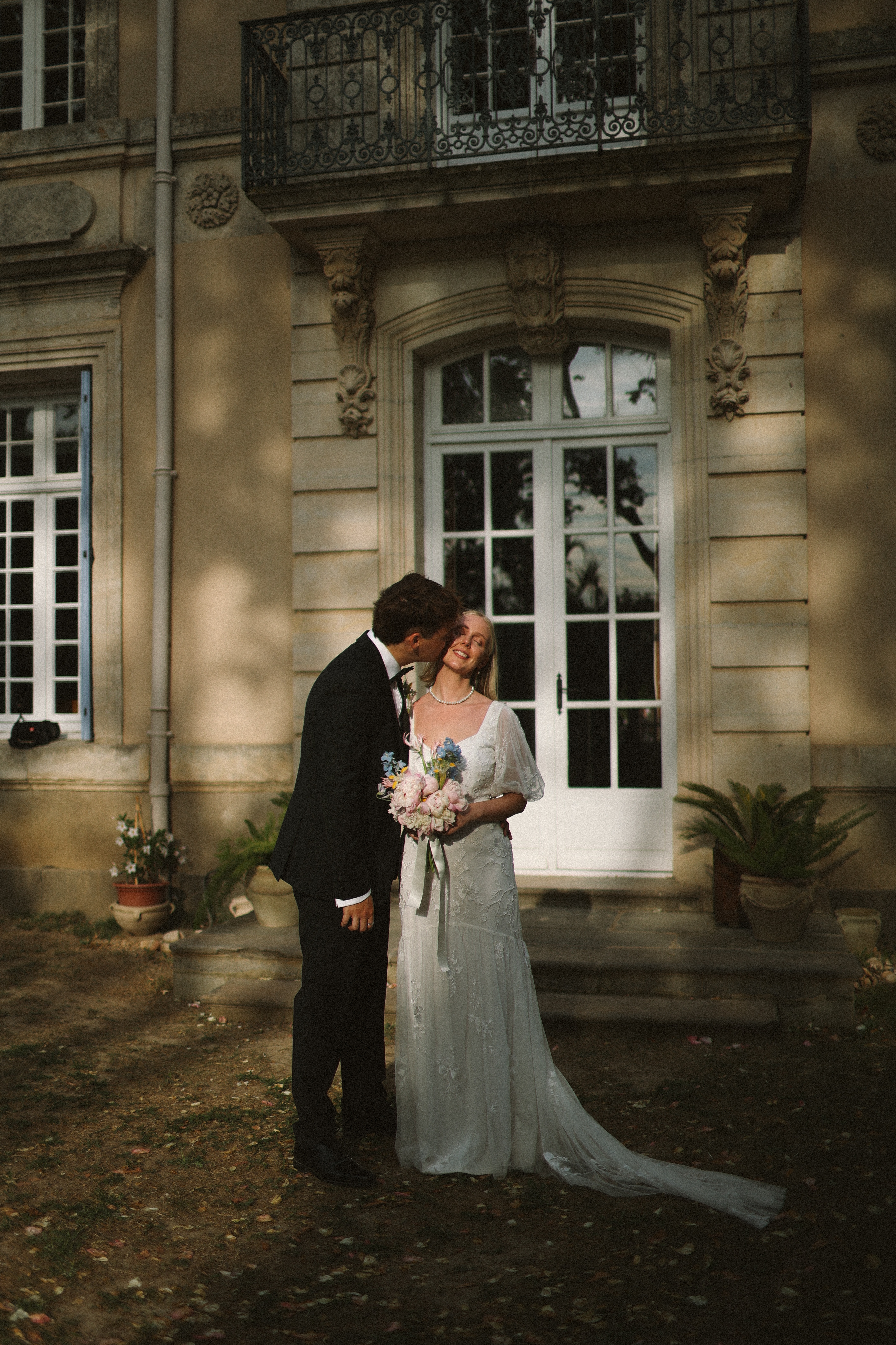Groom kissing bride's cheek at chateau doorway at Chateau du Puits es Pratx, Ginestas