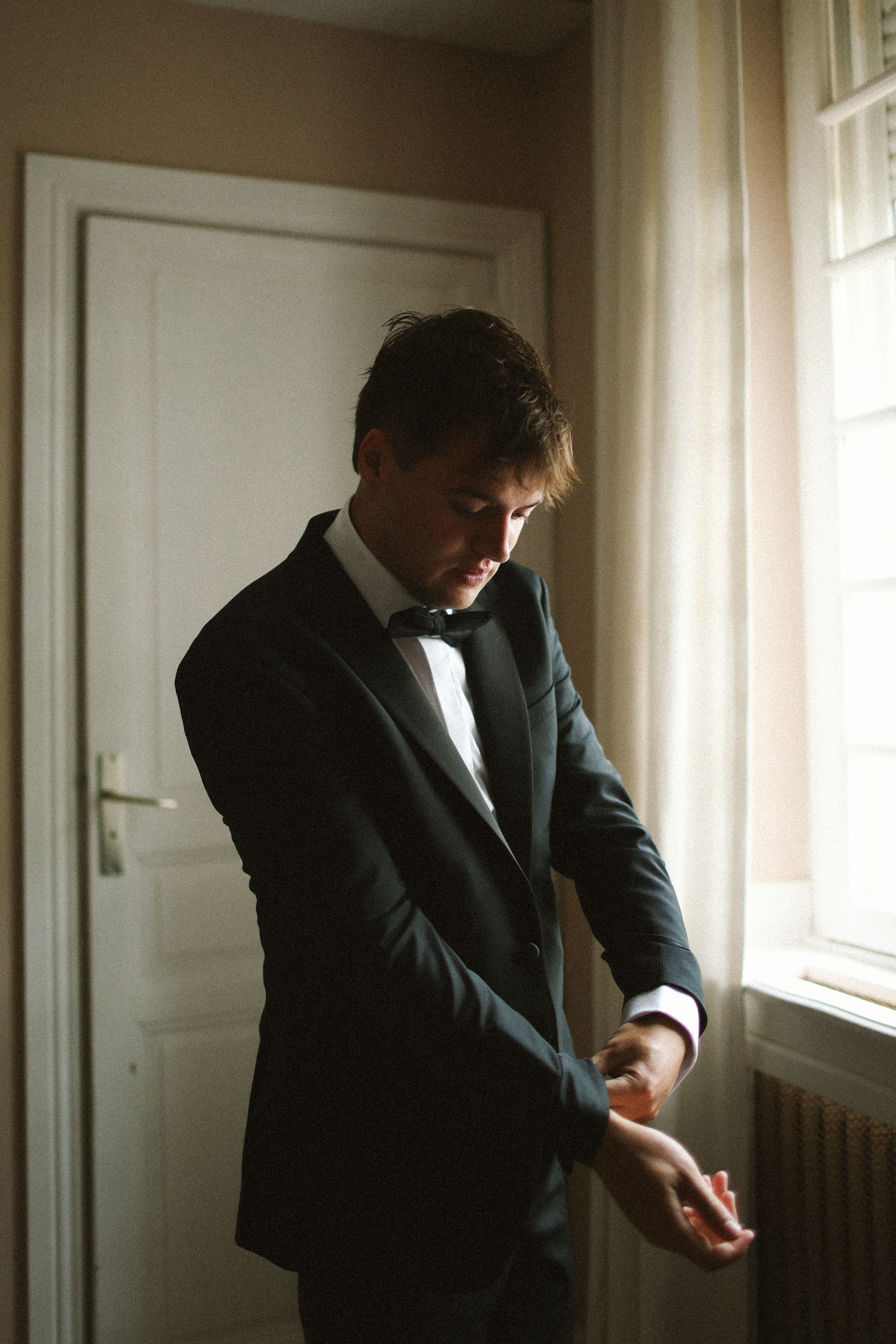 Groom in black tuxedo by window at Chateau du Puits es Pratx, Ginestas