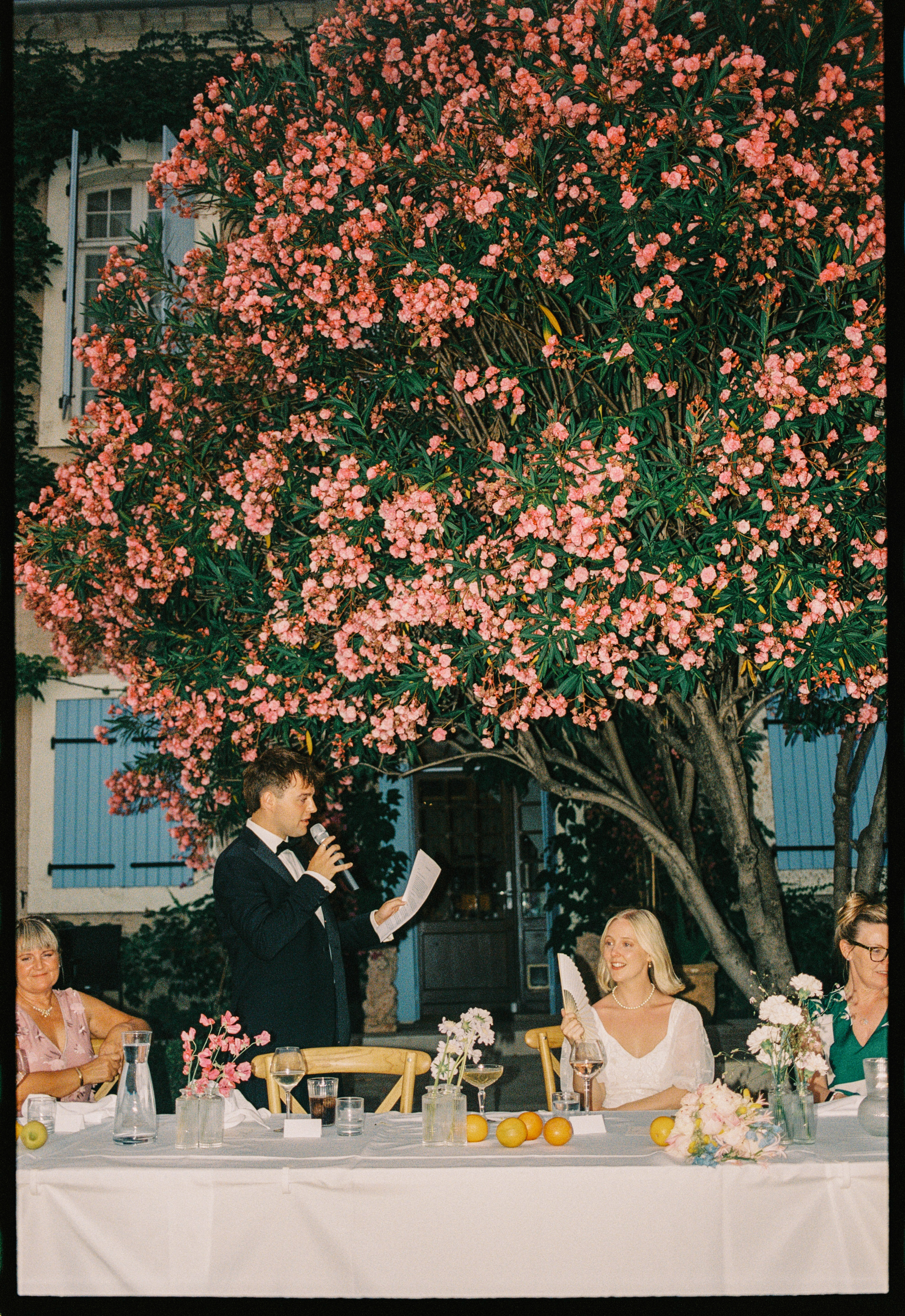Groom giving reception speech under oleander at Chateau du Puits es Pratx, Ginestas