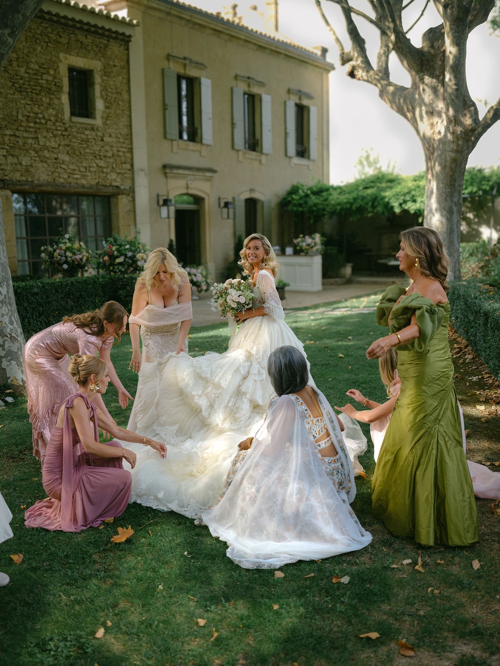bridesmaids gathering the bride's train on the lawn at La Bastide de Laurence, Provence