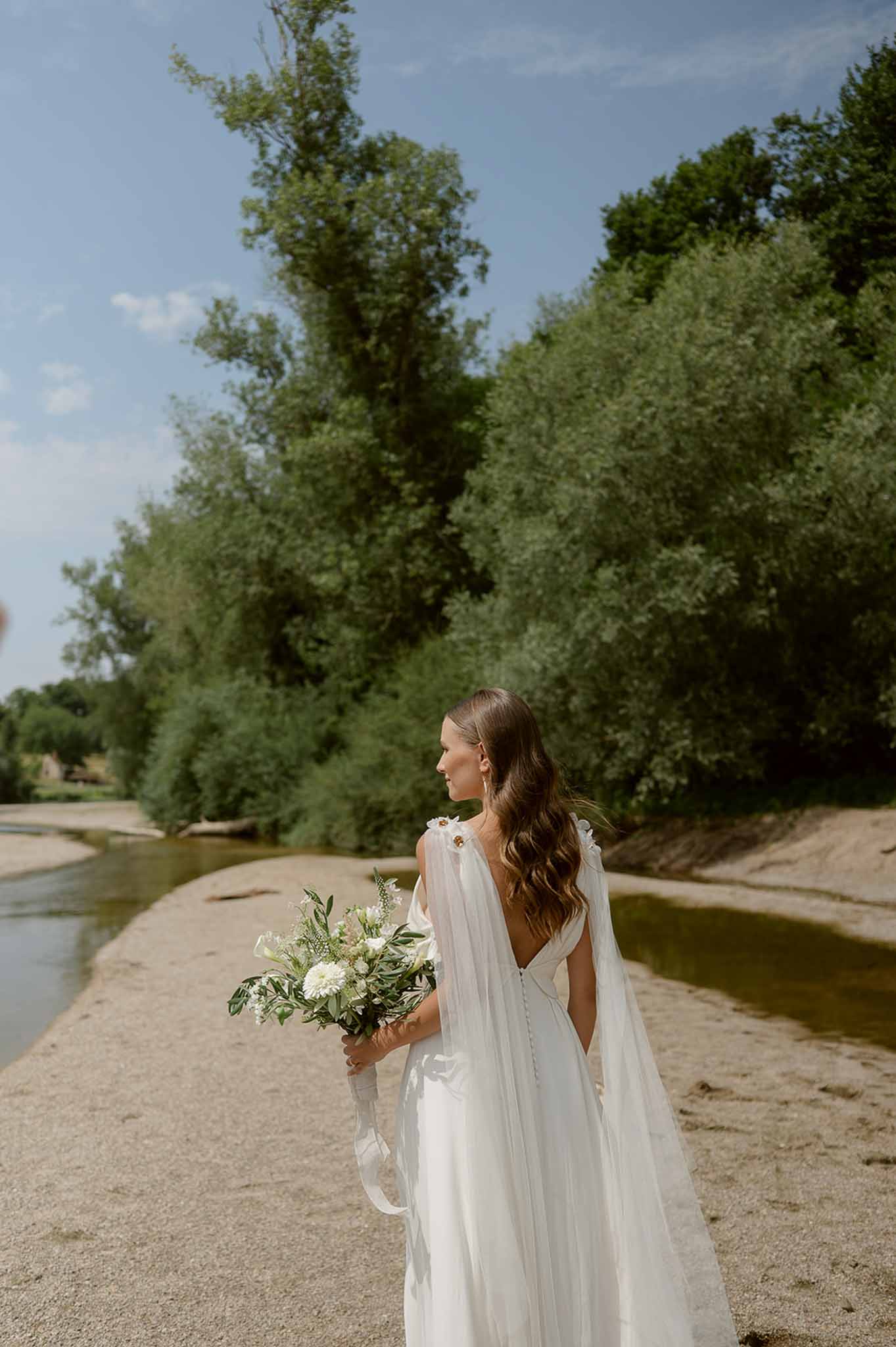 Bride from behind with bouquet on riverbank at Plage d'Apremont-sur-Allier