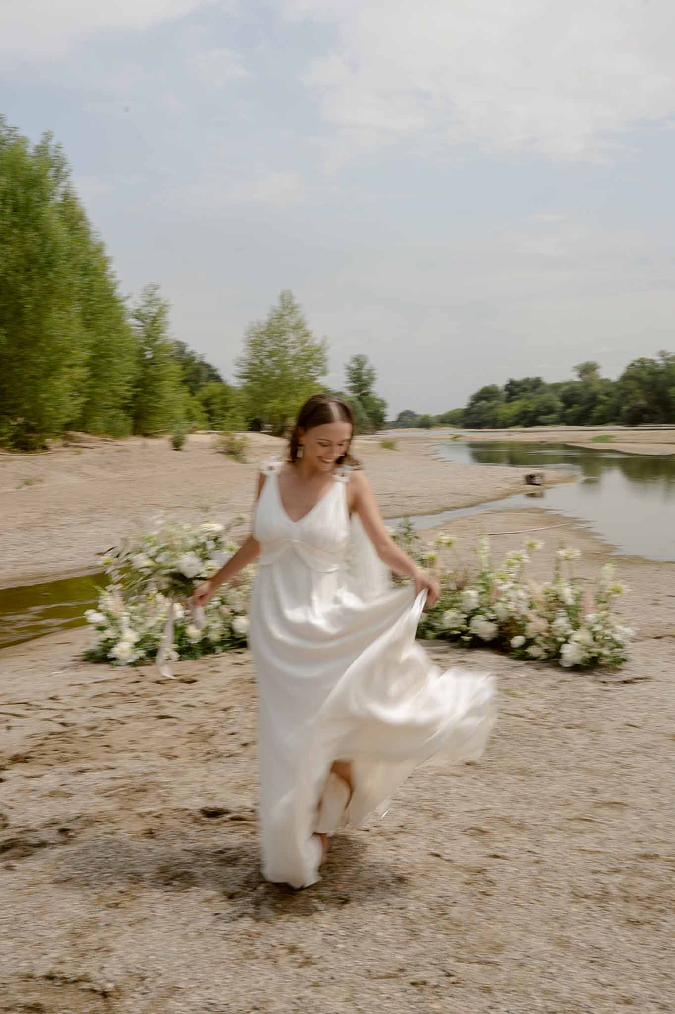 Bride running barefoot near ceremony arch at Plage d'Apremont-sur-Allier