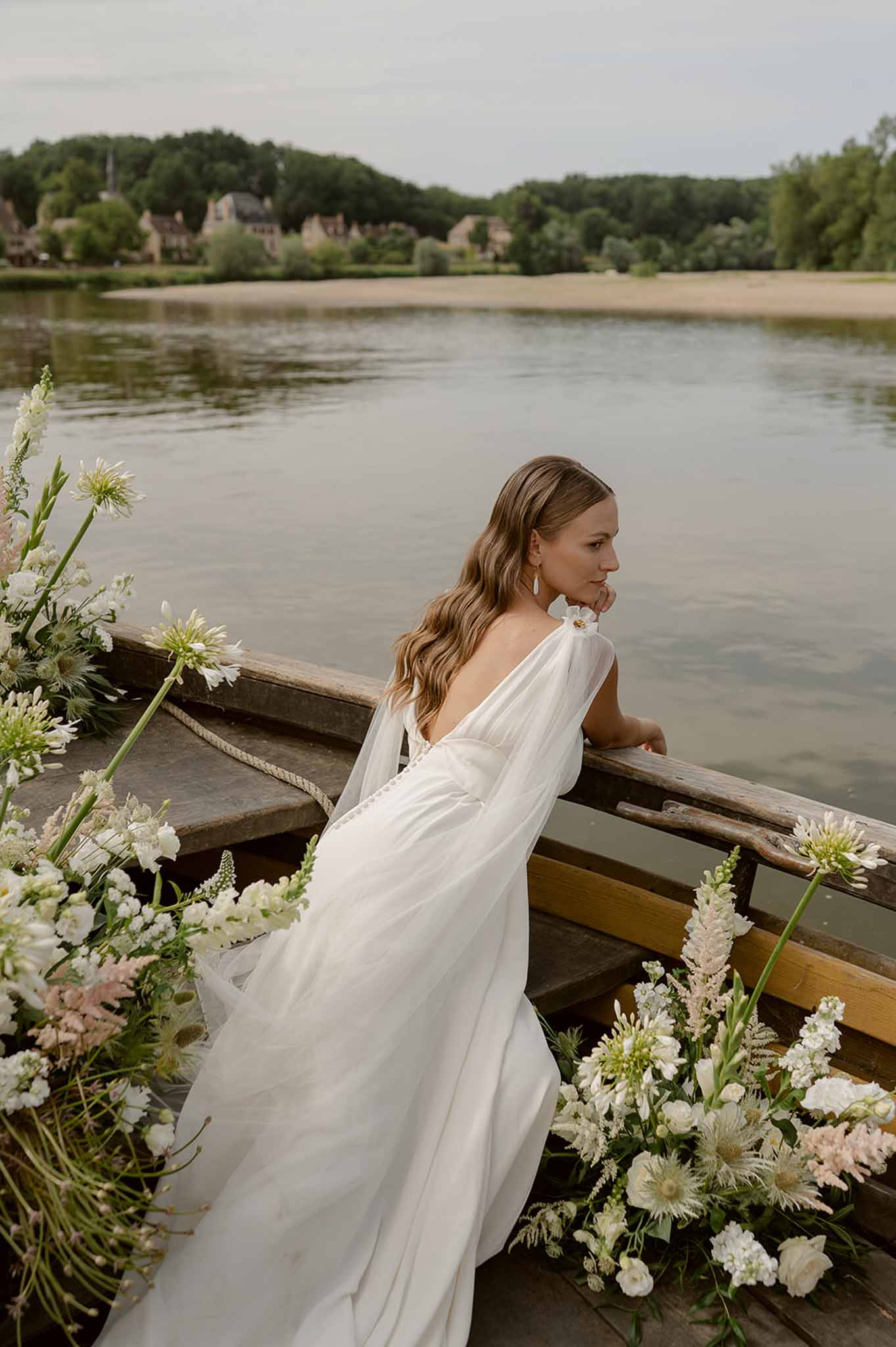 Bride sitting in boat with wild florals on river at Plage d'Apremont-sur-Allier