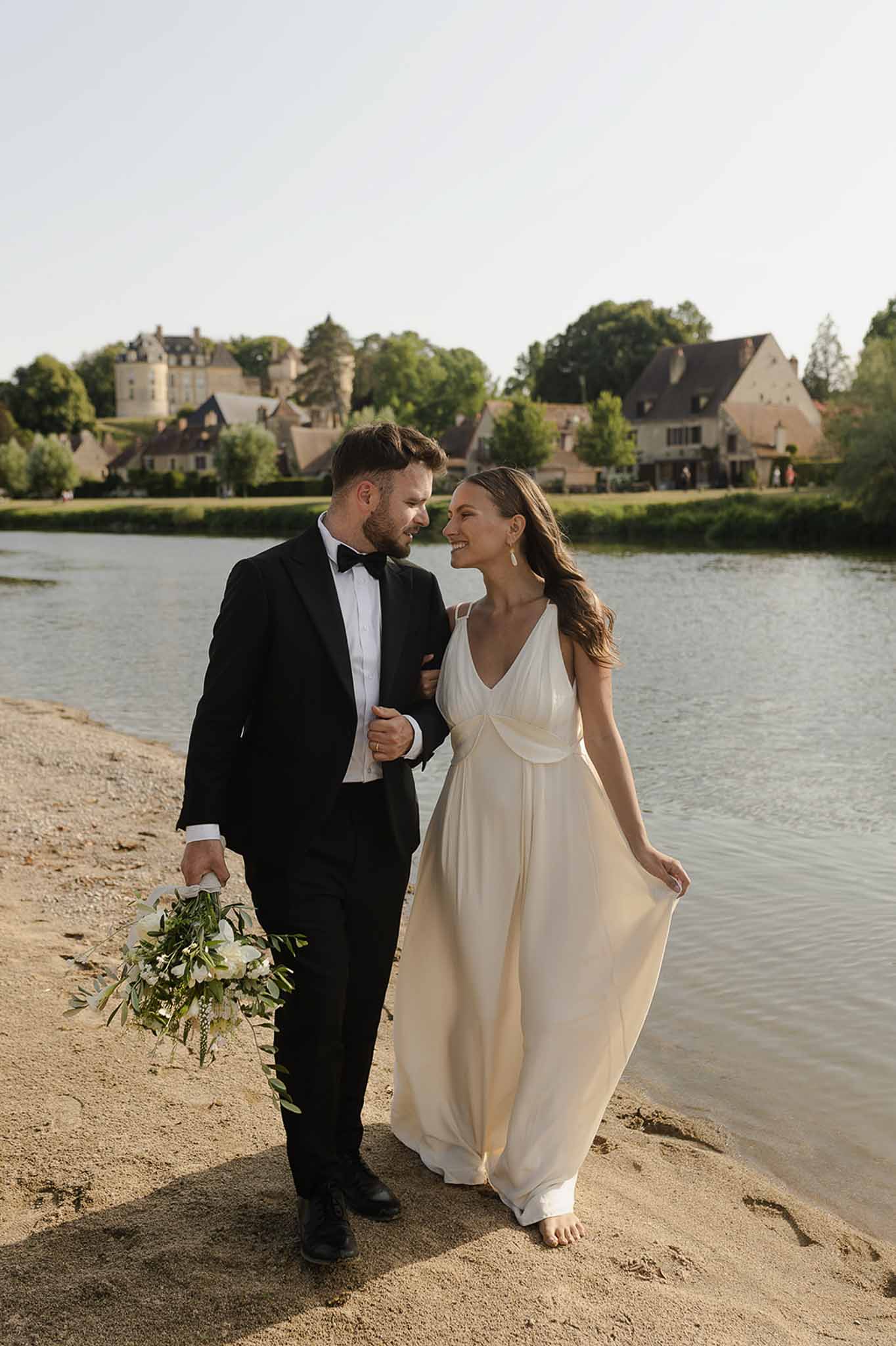 Couple walking along riverbank at golden hour at Plage d'Apremont-sur-Allier
