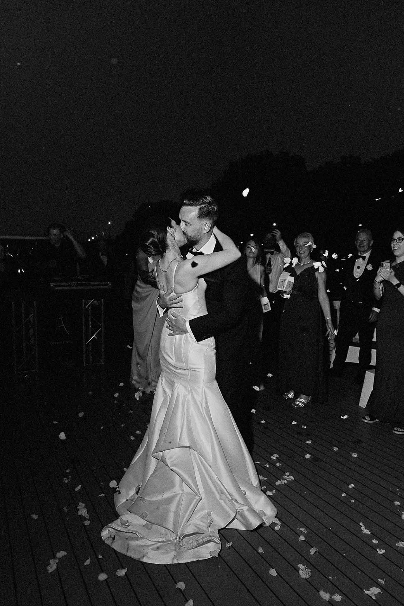 Black and white photo of couple's first dance with white roses