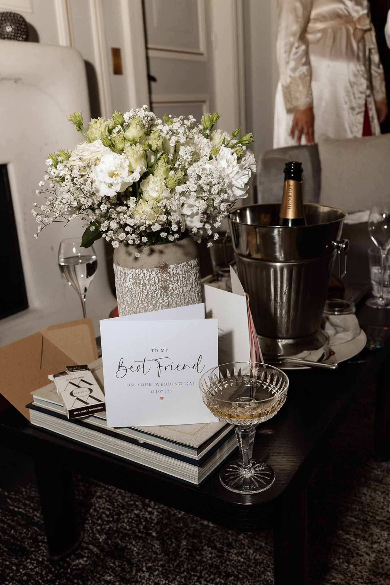 Bridal morning detail with white lisianthus arrangement, wedding day card, and Henriot champagne