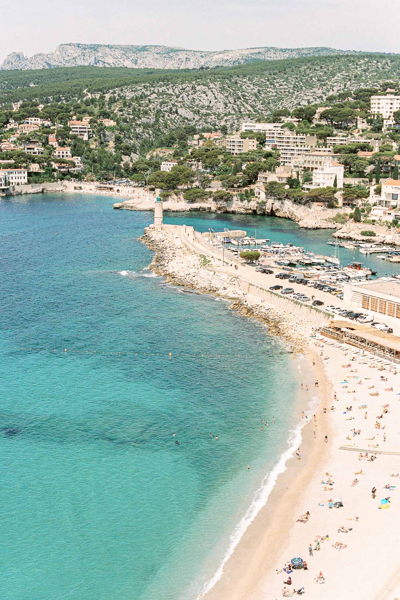 Aerial view of a coastal town with sandy beach, marina, and limestone cliffs in the South of France