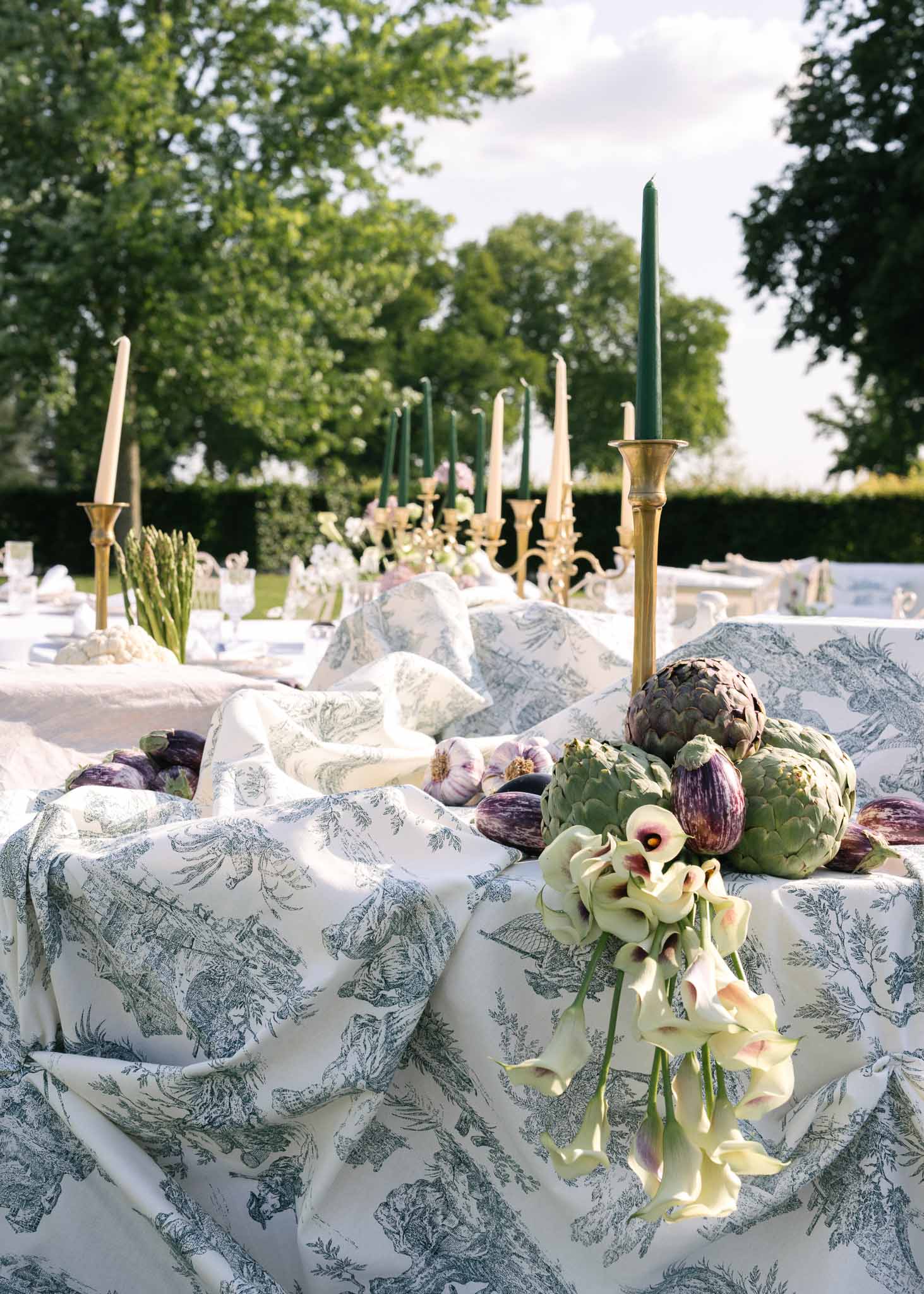 Toile de Jouy tablecloth with artichoke and fig centerpiece, calla lilies, and brass candelabras
