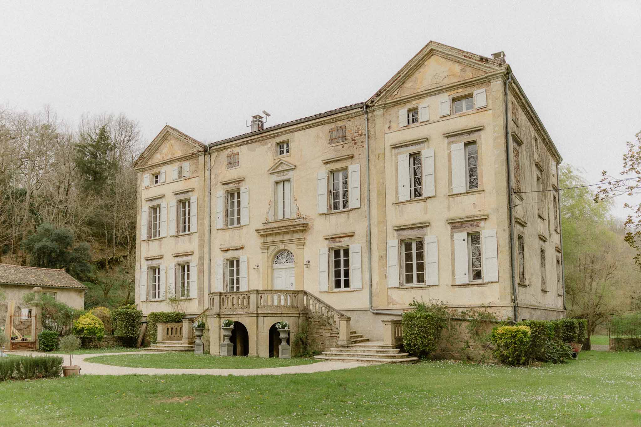 Three-storey French chateau with ochre walls, grey shutters, and grand double staircase entrance