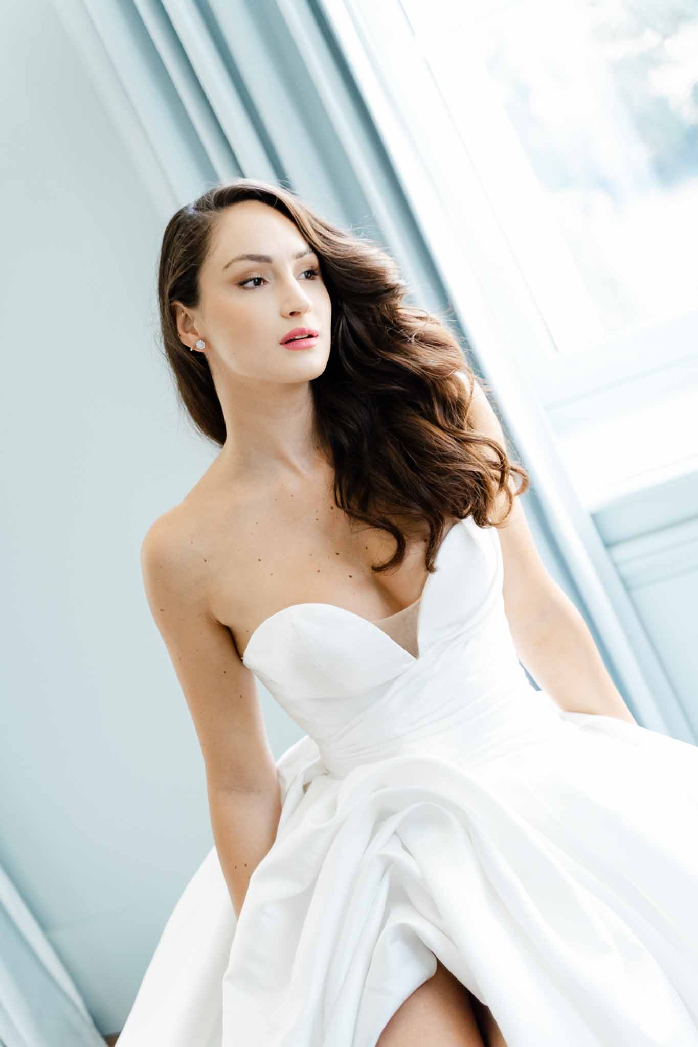 Close-up portrait of bride in strapless sweetheart ballgown with loose waves and coral lip