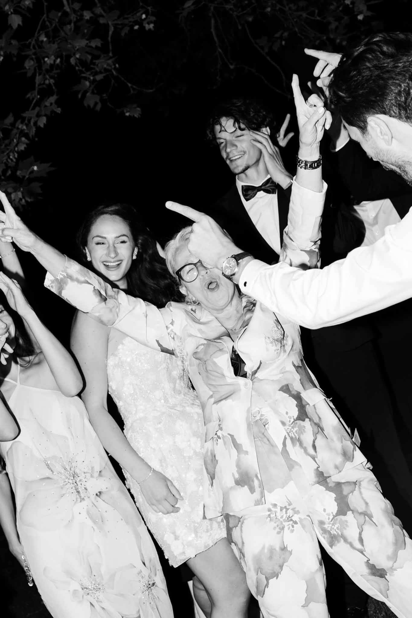 Wedding guests dancing energetically at evening reception captured in high-contrast black and white