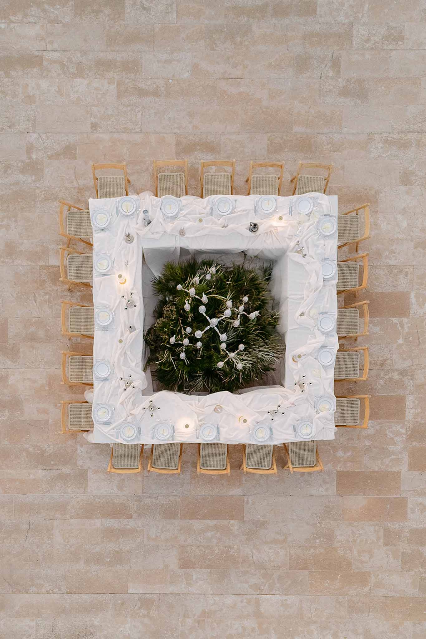 Aerial overhead view of hollow-square table with dense fern greenery center and rattan chairs
