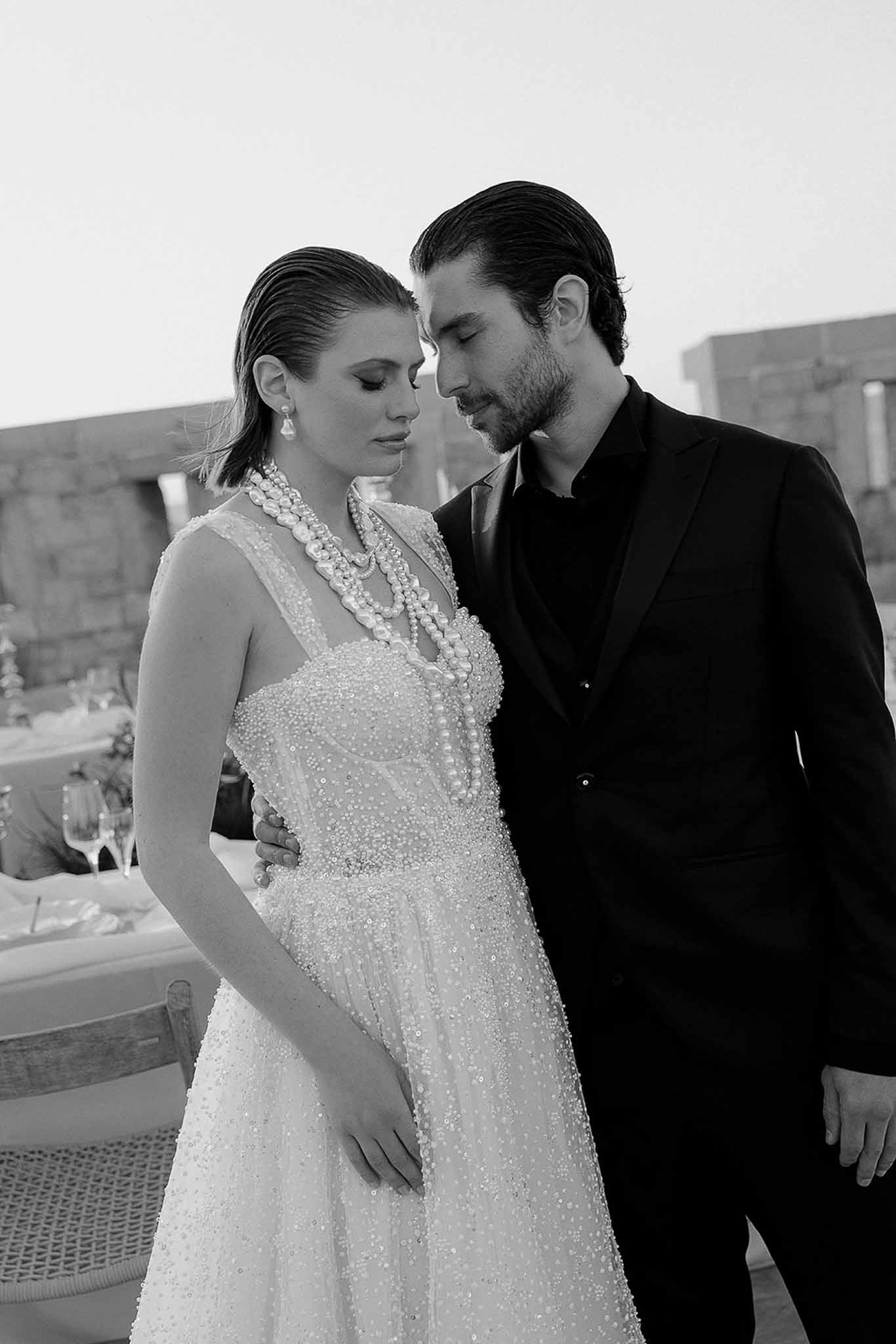 Black and white intimate portrait of couple at dusk, bride in beaded gown with pearl necklace and earrings