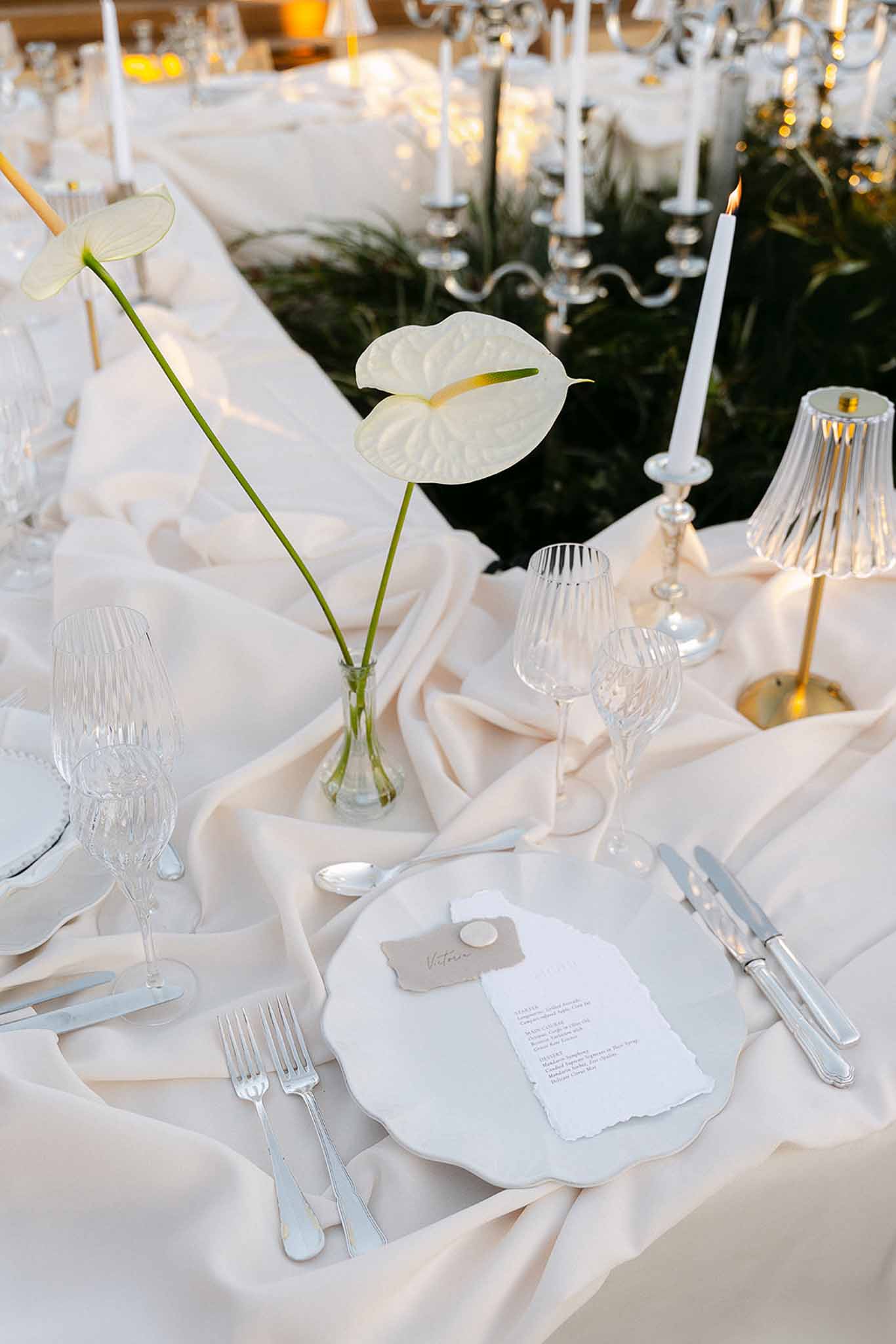 Minimalist table setting with white anthurium bud vases ivory silk runner and deckle-edge menu cards