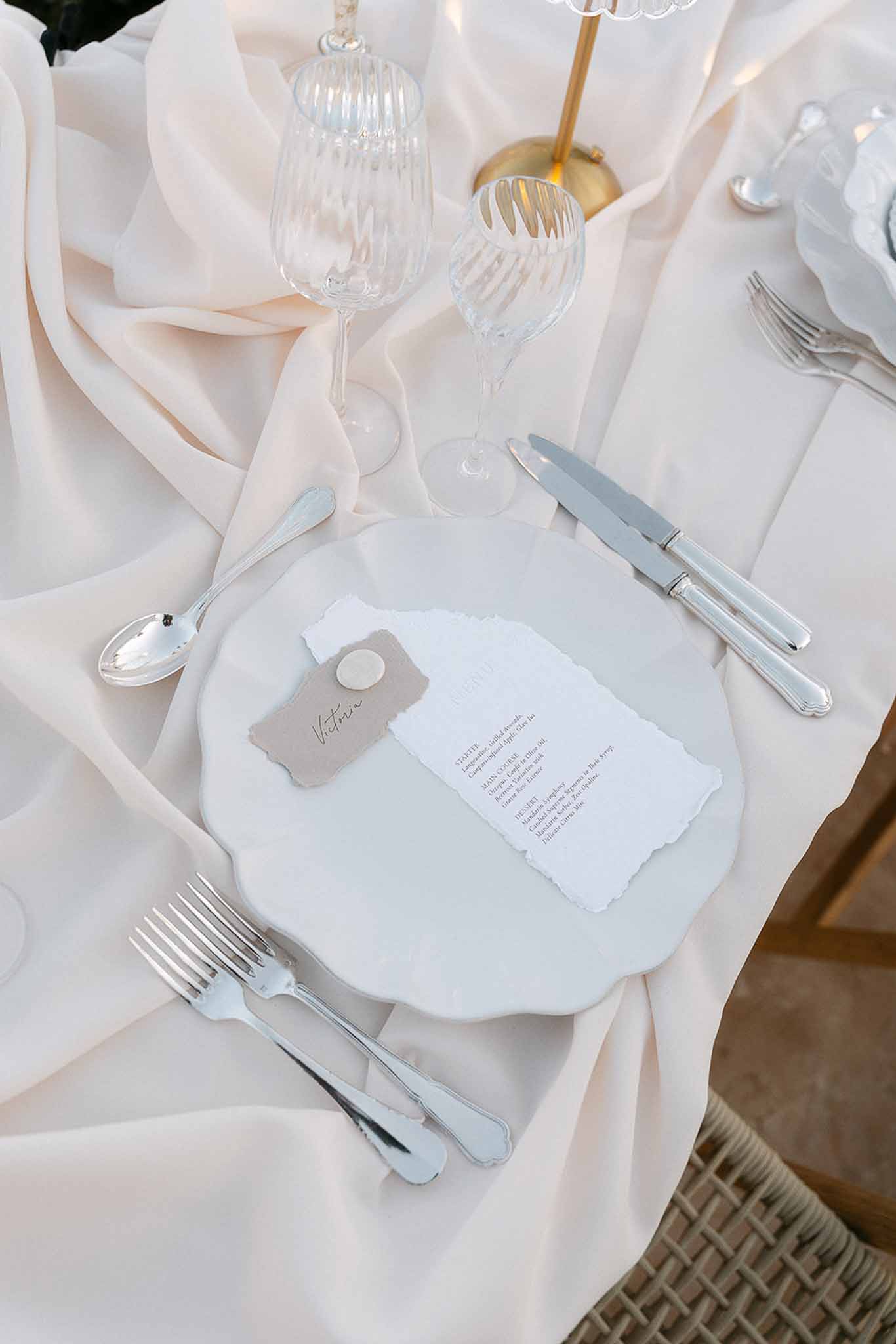 Minimal place setting with torn-edge menu card wax seal taupe place card on ivory silk runner