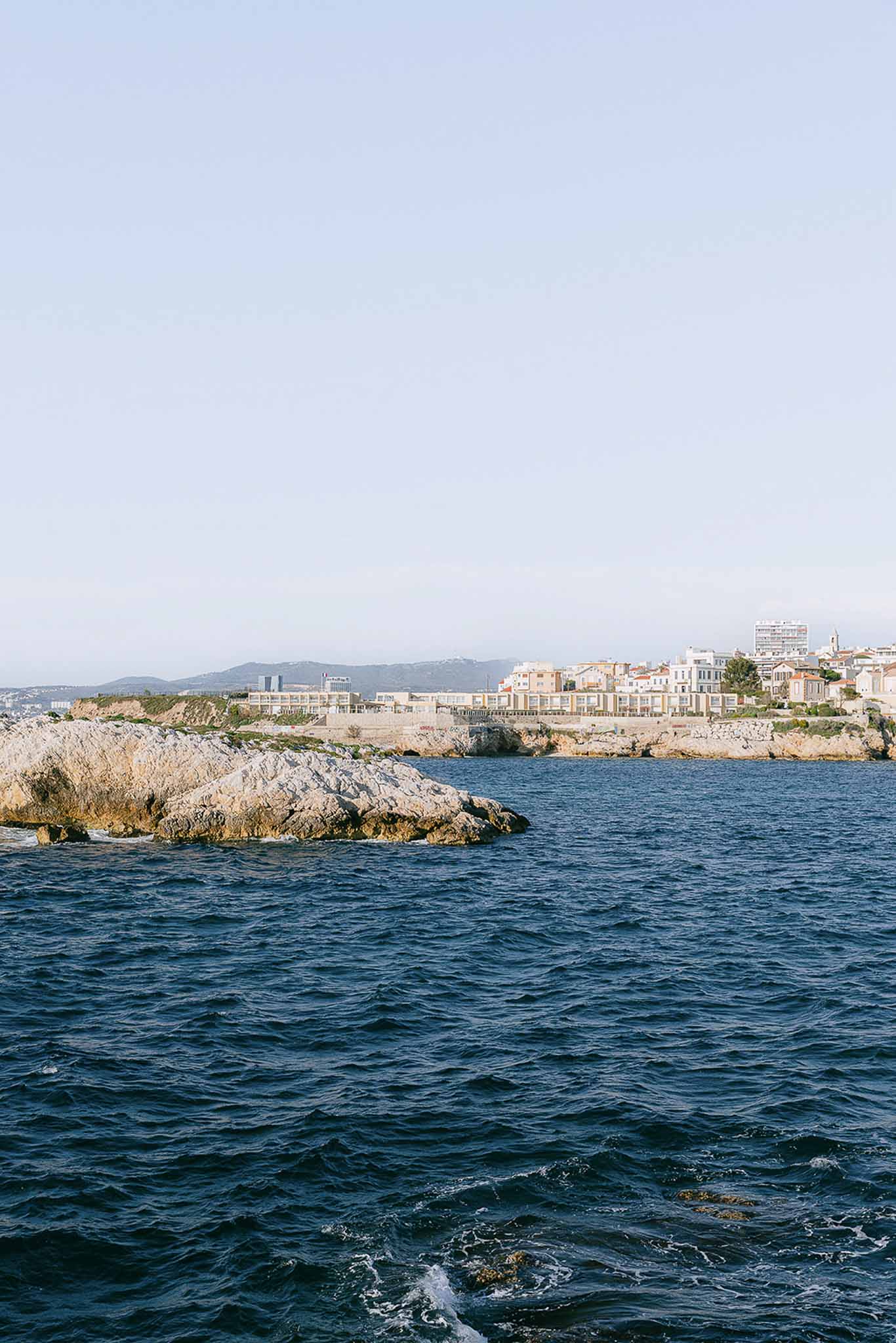 Mediterranean coastal village with white and terracotta buildings on rocky promontory from sea level