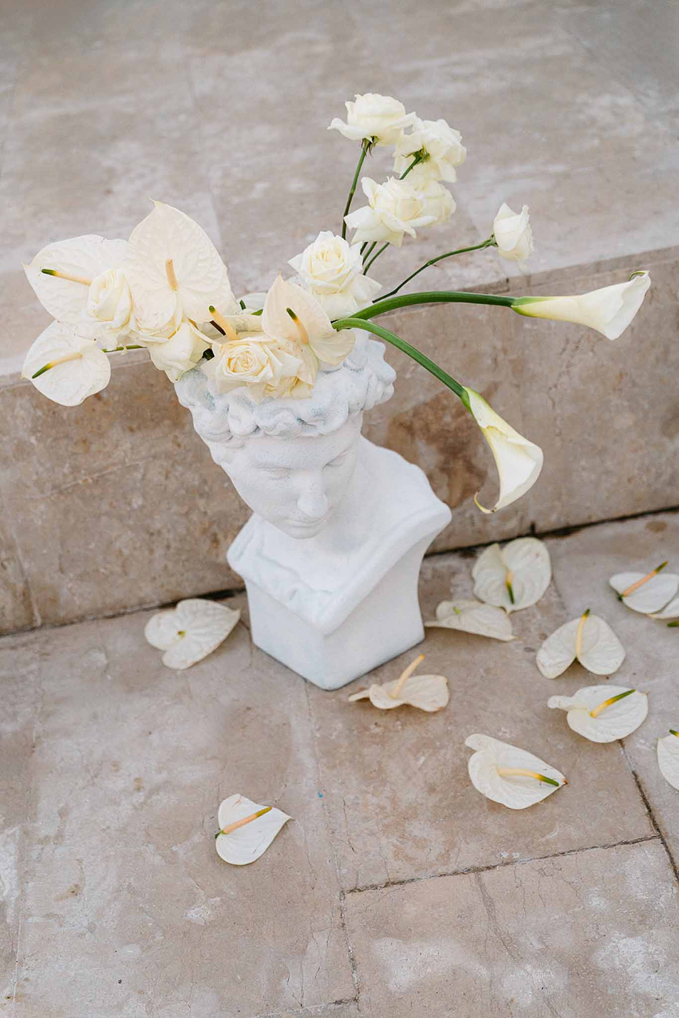 White ceramic bust vase with cream anthurium, calla lily, and spray rose arrangement