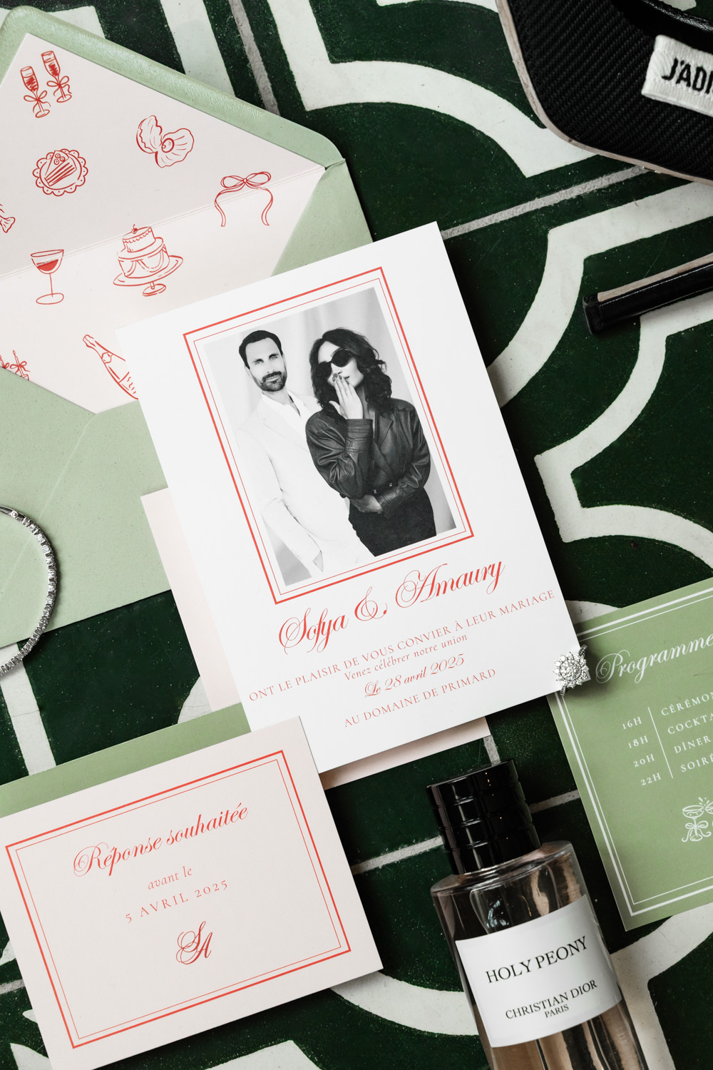 Wedding stationery suite in sage green and red with Dior perfume, tennis bracelet, and programme card