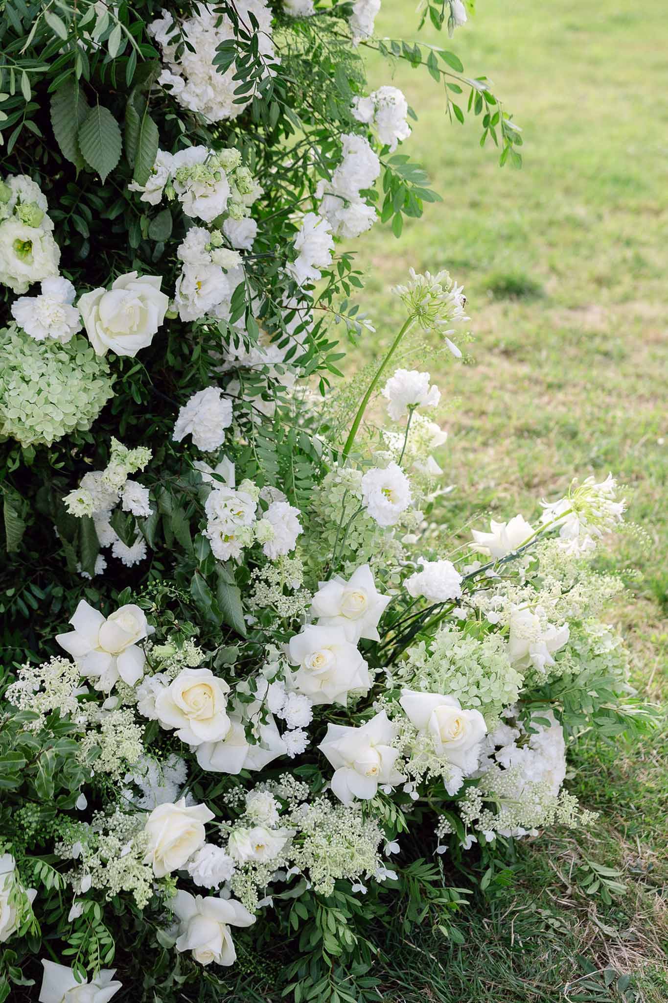 Close-up of white garden rose, hydrangea, and lisianthus ceremony floral installation with fern and eucalyptus foliage