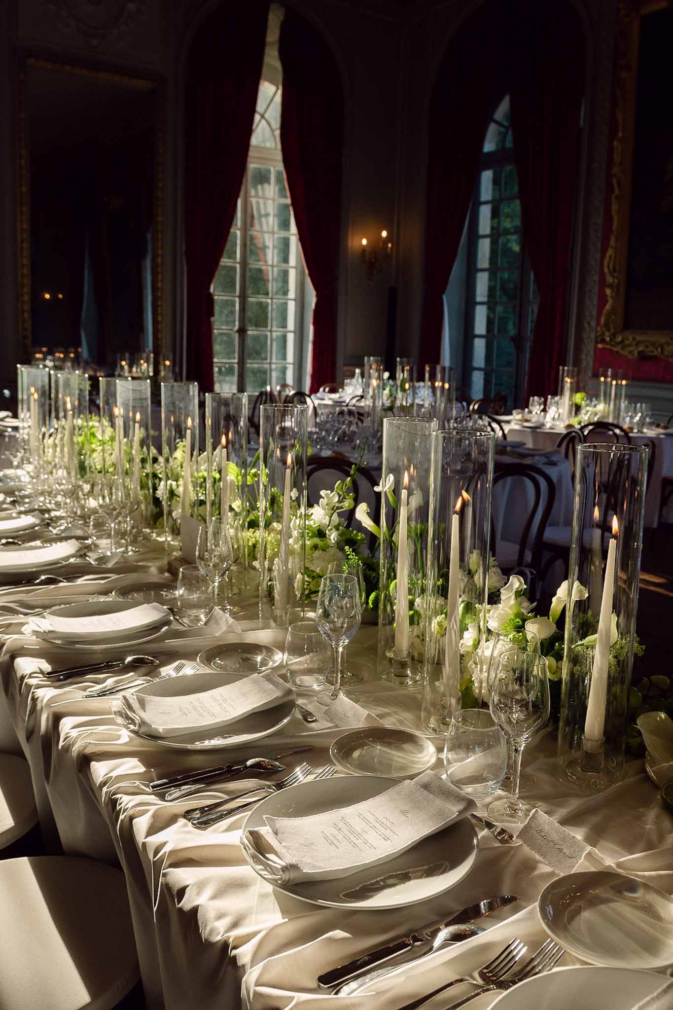 Formal reception table with white calla lily centerpieces, taper candles, and ivory satin cloth in chateau ballroom
