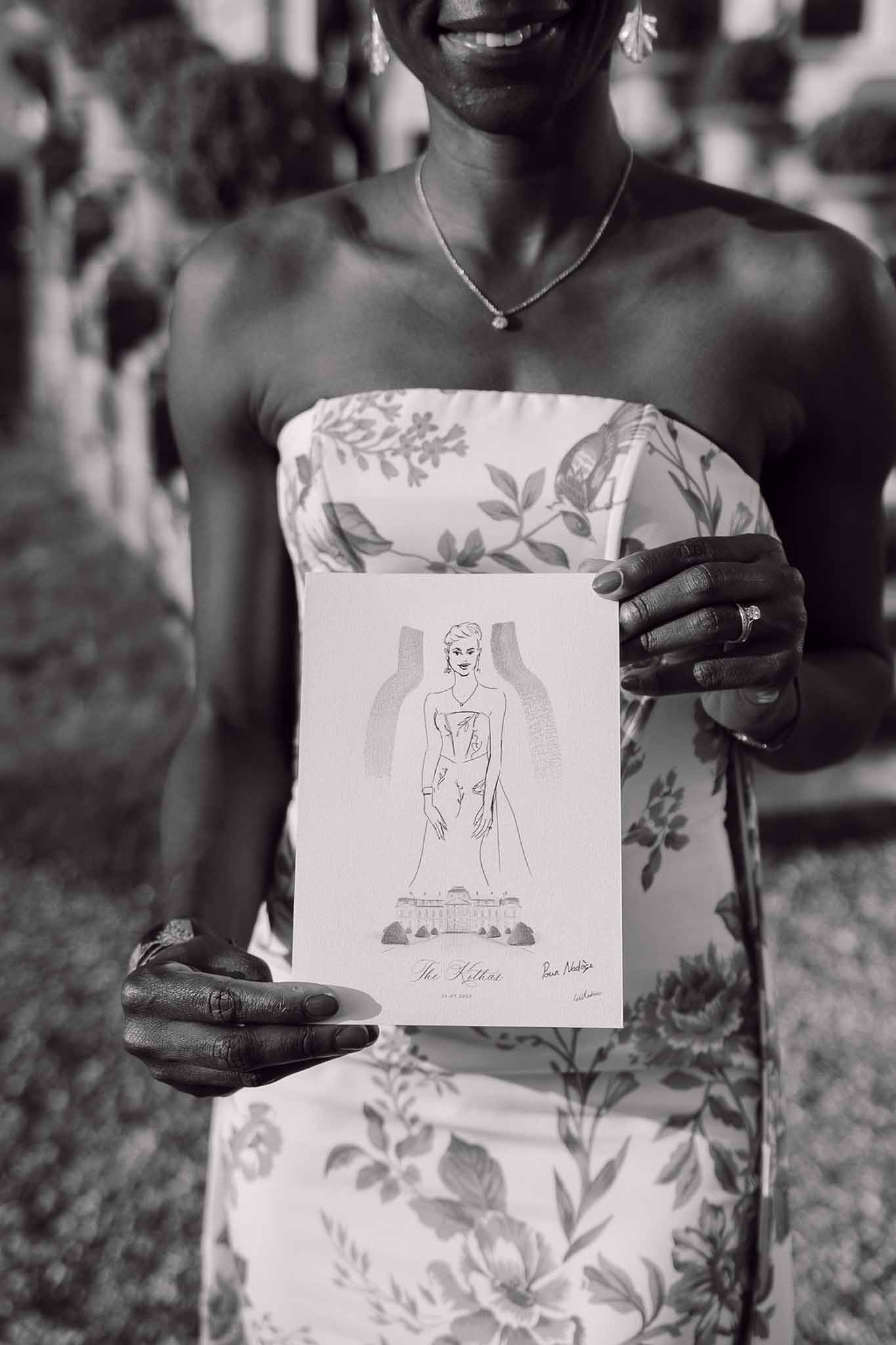 Black and white guest holding custom illustrated wedding keepsake card with chateau drawing at ceremony