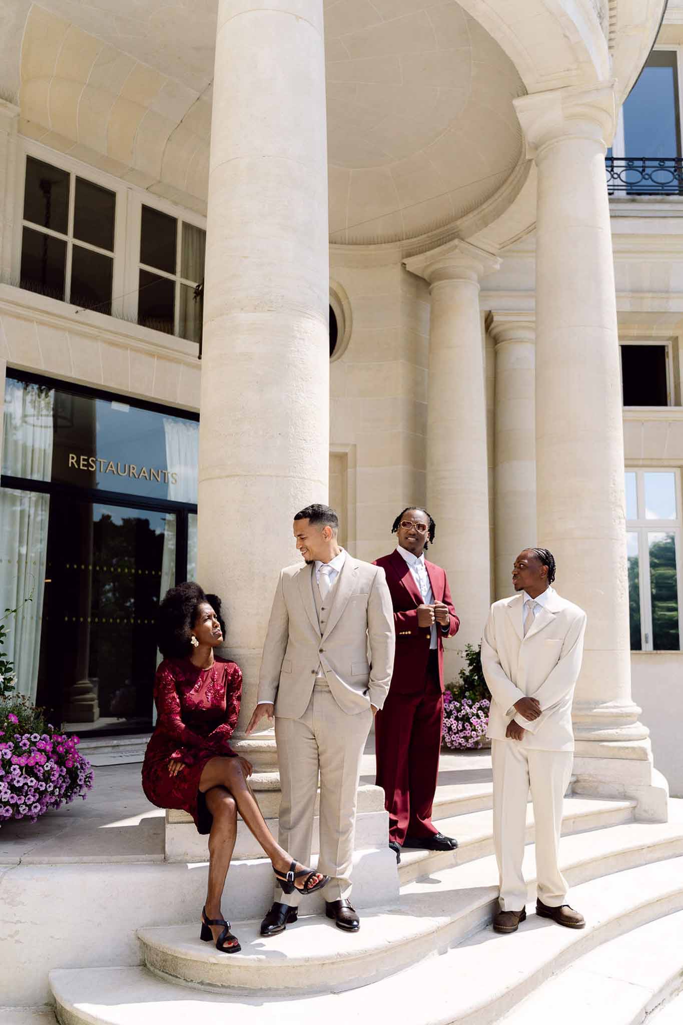 Groom and three wedding party members posing on stone steps of neoclassical venue with white columns