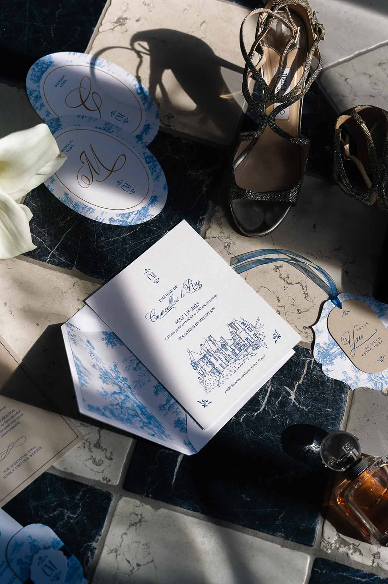 Navy toile de Jouy stationery suite with gold monogram fans, glitter heels, and calla lily on marble tile