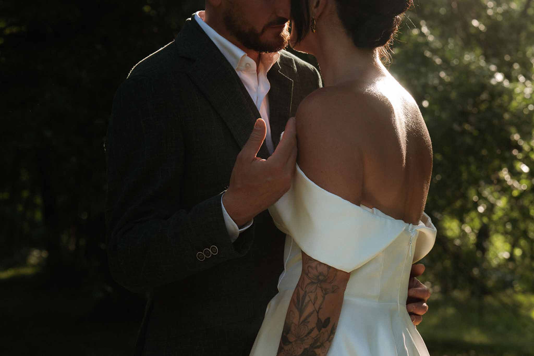 Close-up of bride and groom kissing at golden hour with warm backlight creating a halo effect around the couple