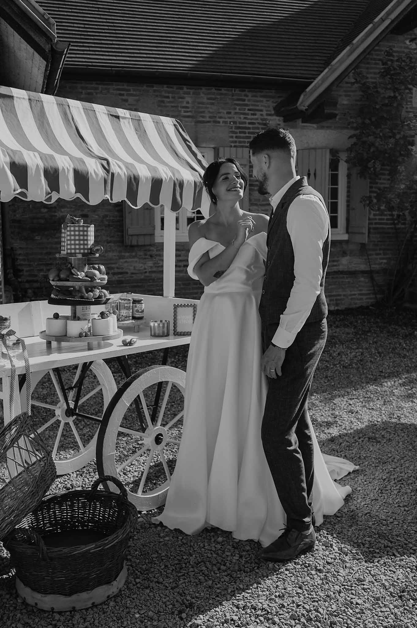 Black and white couple portrait beside white market cart food station at countryside venue