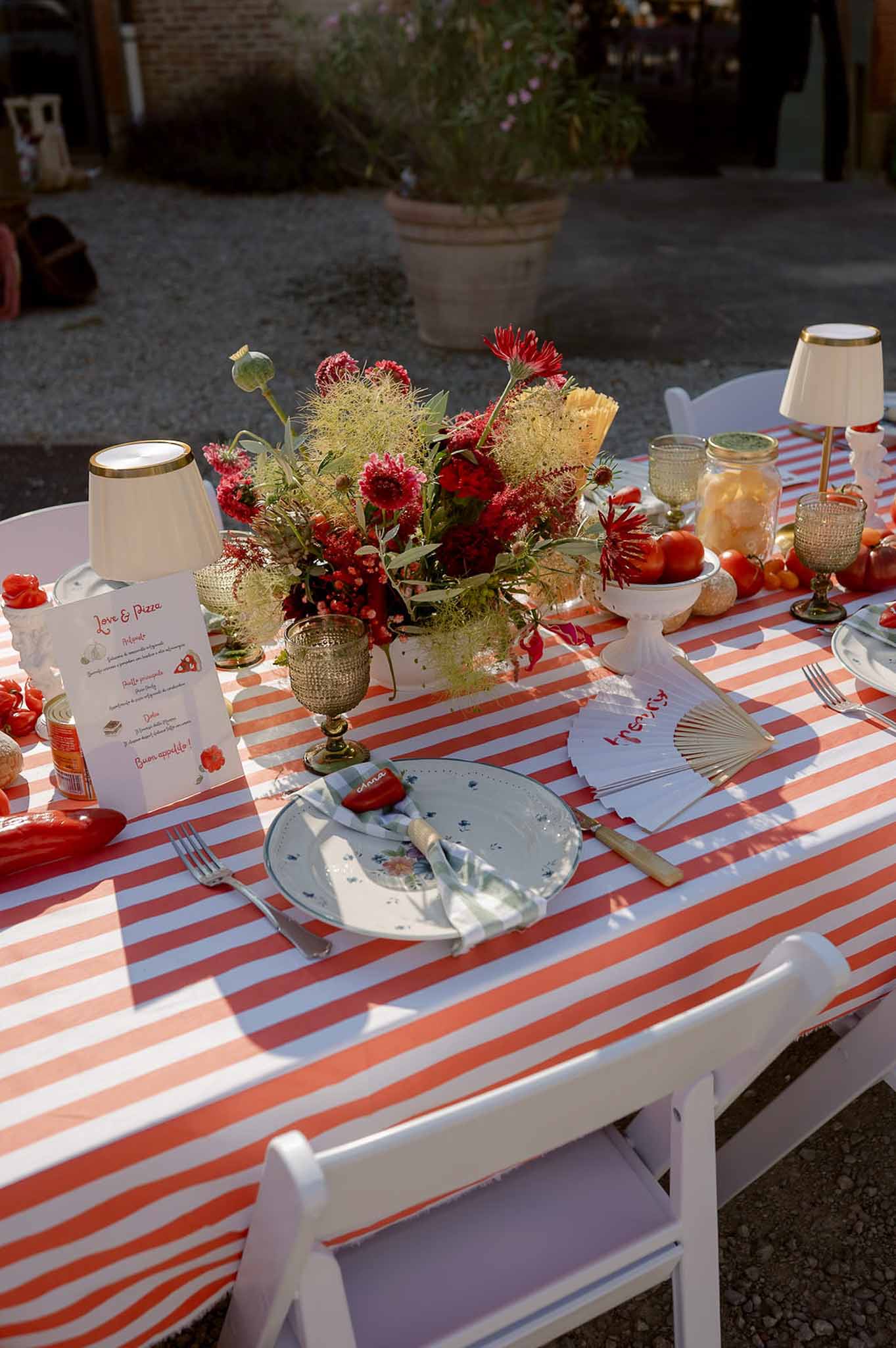 Italian-themed red stripe table with chrysanthemum centerpiece, Love and Pizza menu, and pepper napkins
