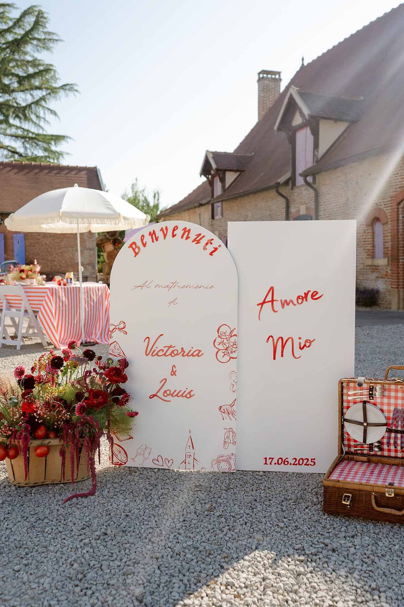 Italian-themed welcome display with hand-lettered signage, burgundy florals, and red gingham table linens