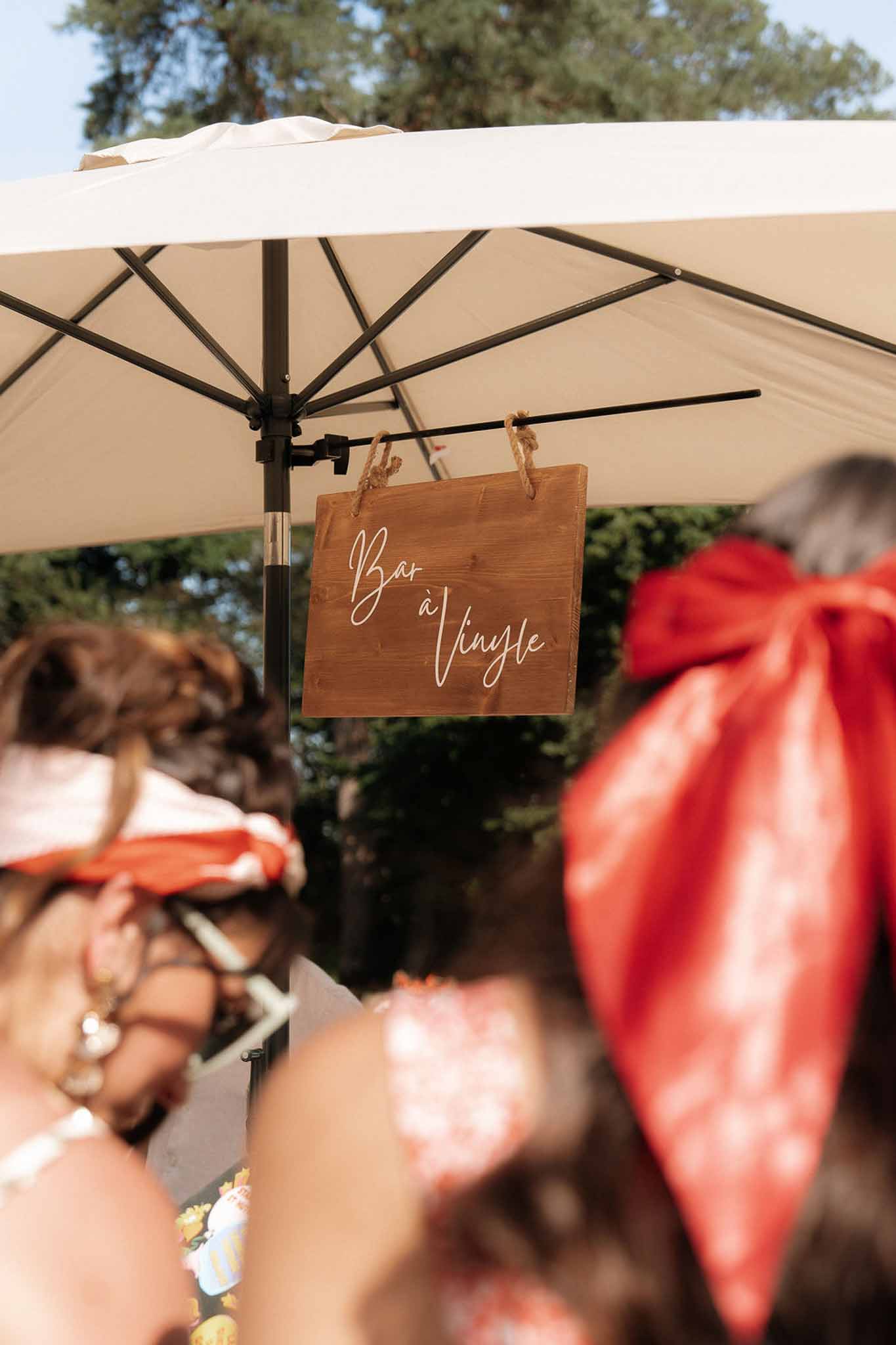 Wooden Bar a Vinyle sign hanging from a market umbrella at an outdoor wedding reception