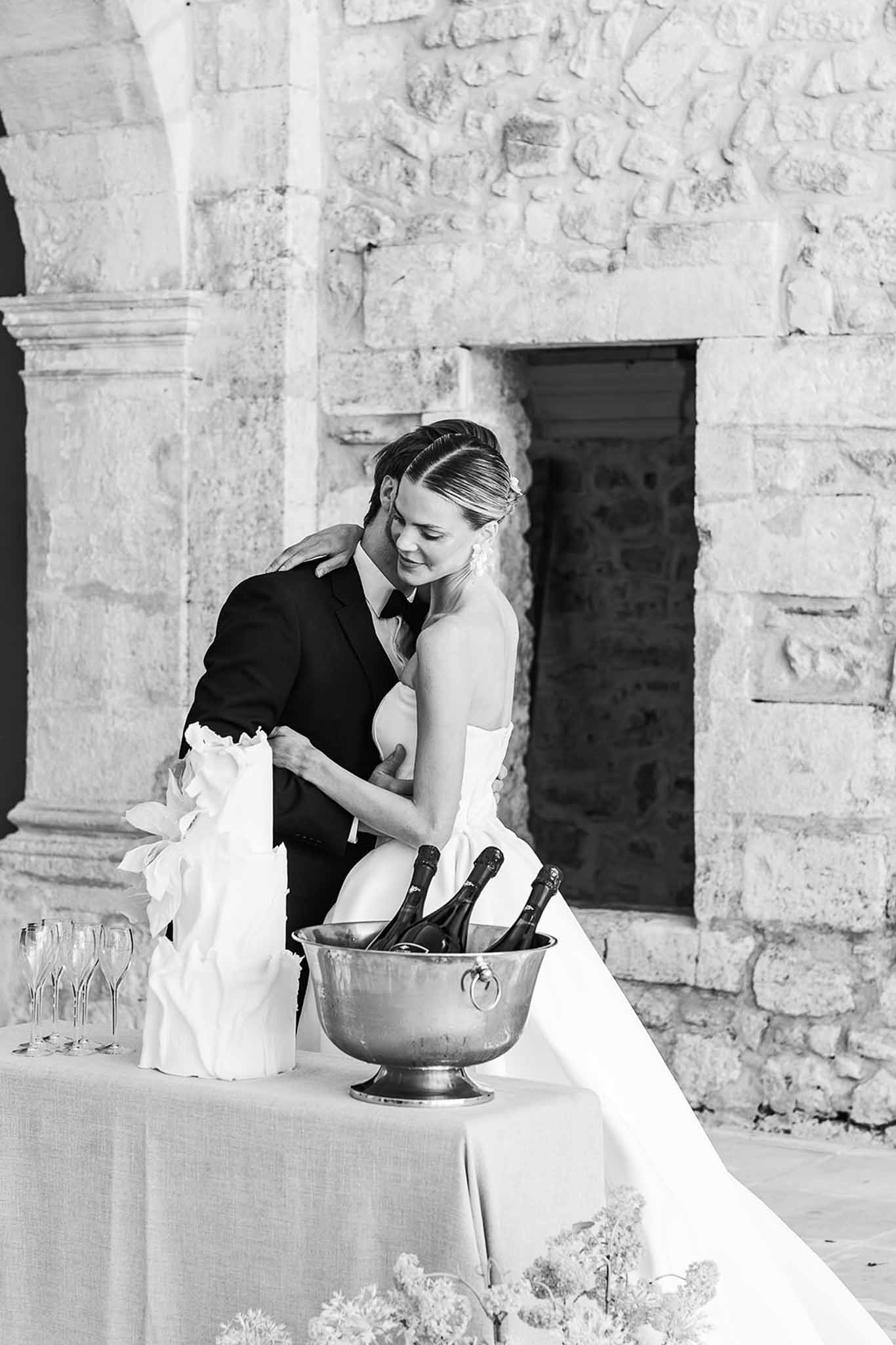 Black and white portrait of couple by stone fireplace with champagne bucket and flute glasses