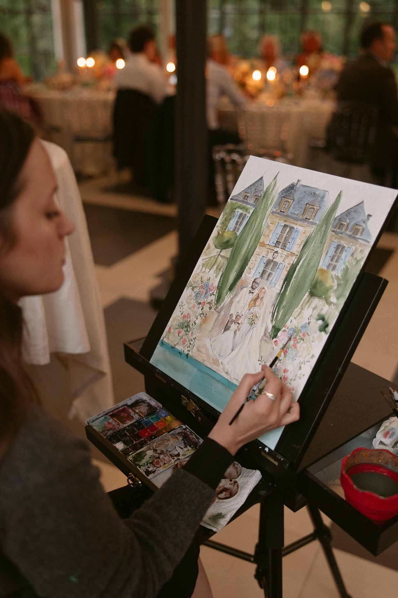 Live wedding artist painting a watercolor portrait of bride and groom during chateau reception