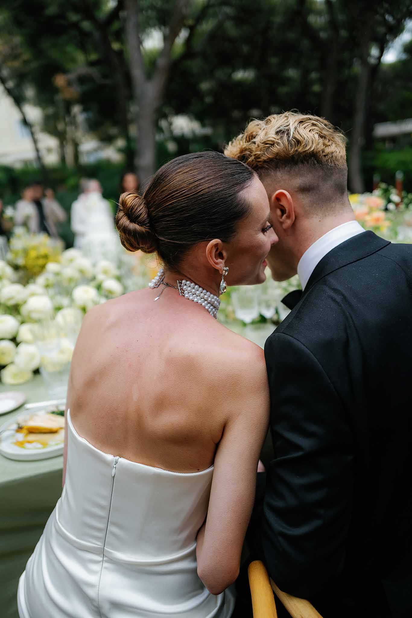 Bride and groom foreheads touching at reception table with sage linen and ivory rose arrangements