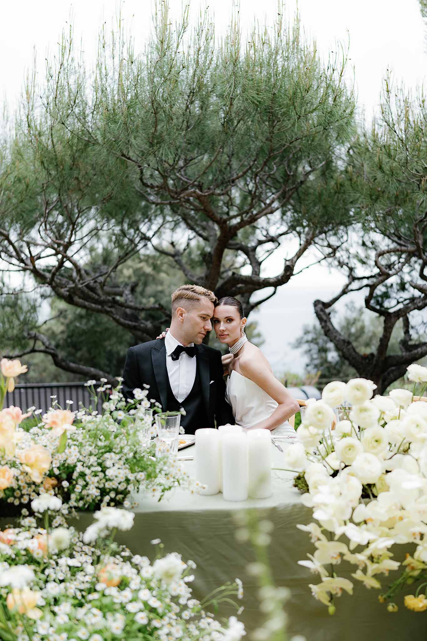 Bride and groom at sweetheart table with white ranunculus peach tulip and orchid floral runner