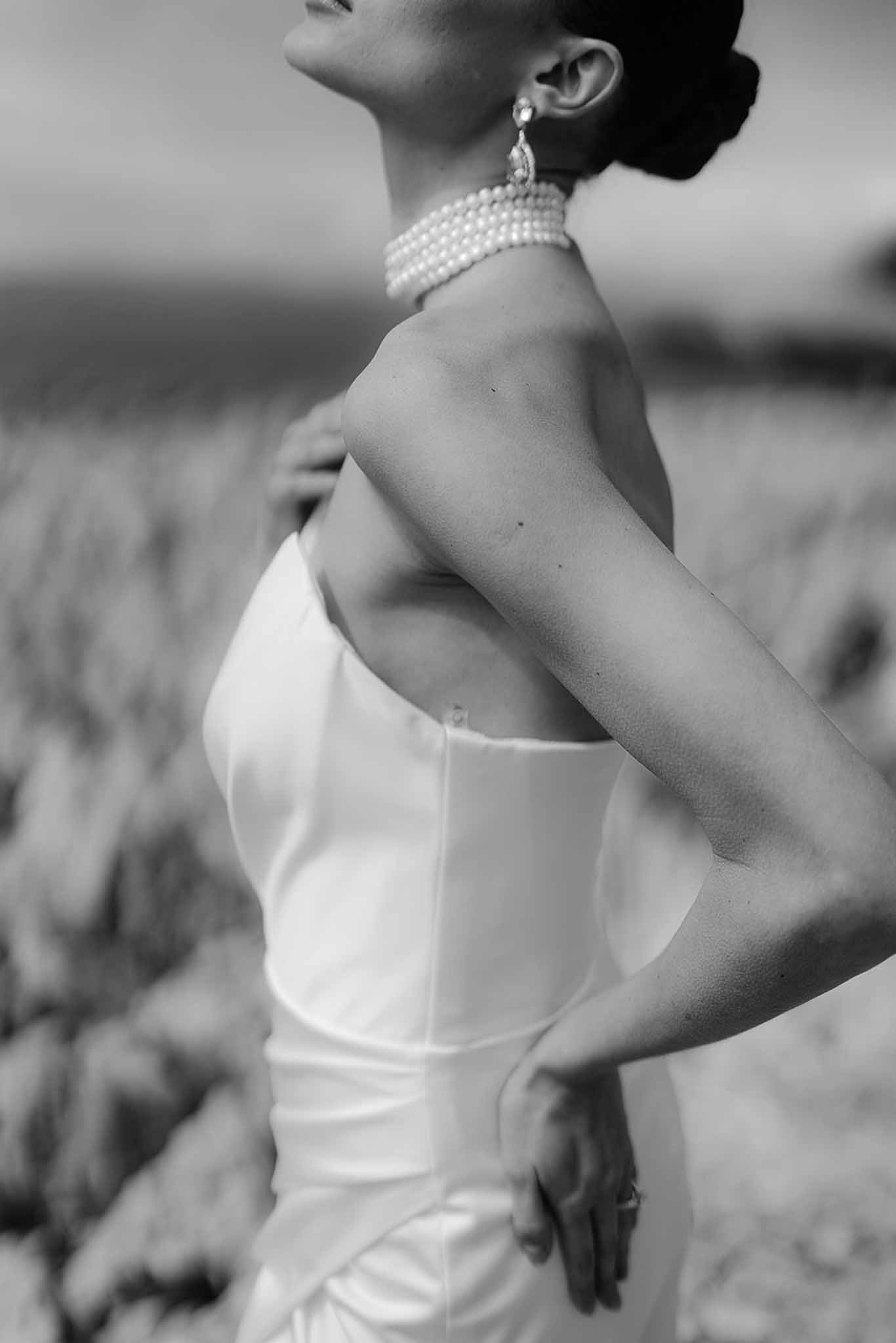 Black and white side profile close-up bride in strapless corset gown with pearl choker and crystal drop earring