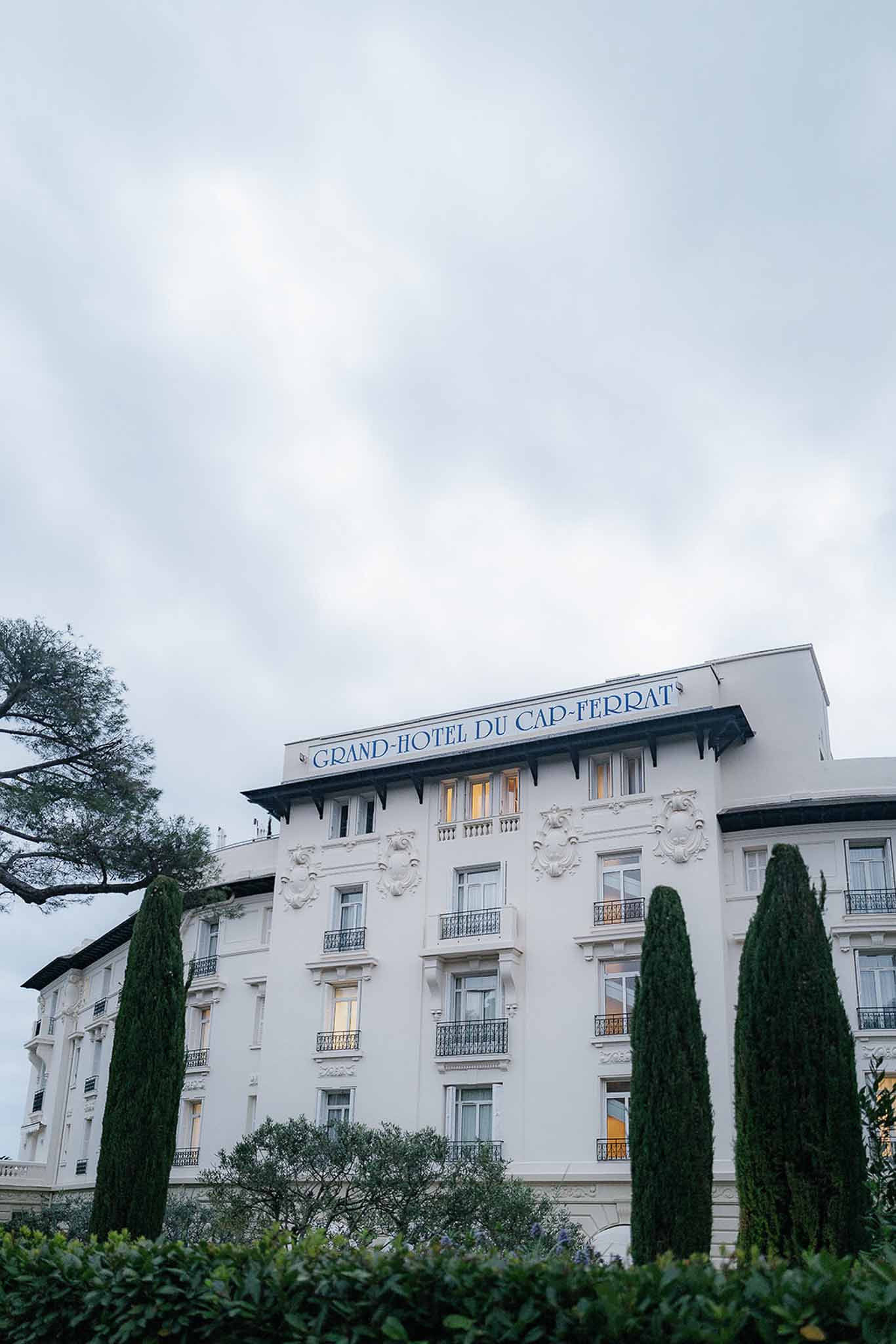 Grand-Hotel du Cap-Ferrat white Belle Epoque facade with Juliet balconies and cypress trees at dusk