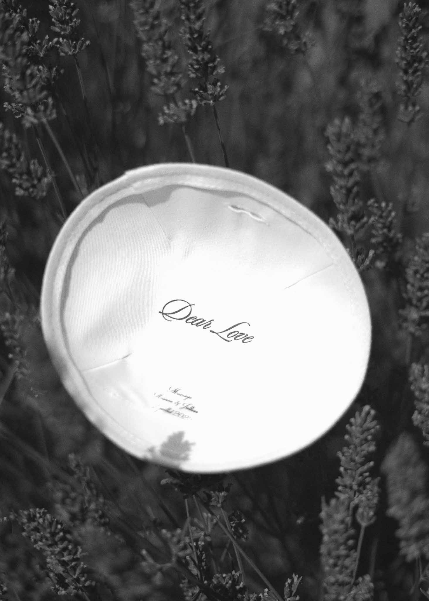Black and white close-up of 'Dear Love' label inside wedding dress lining laid among lavender stems