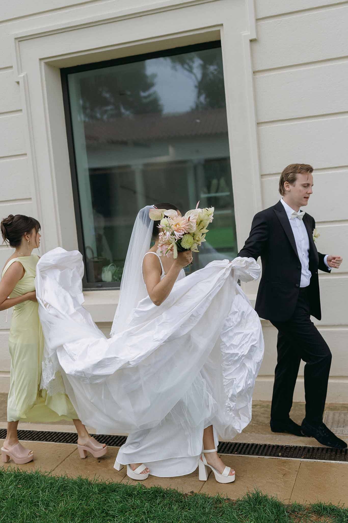 Bride walking with groom and bridesmaid carrying dress at Domaine Rocabella, Cote d'Azur