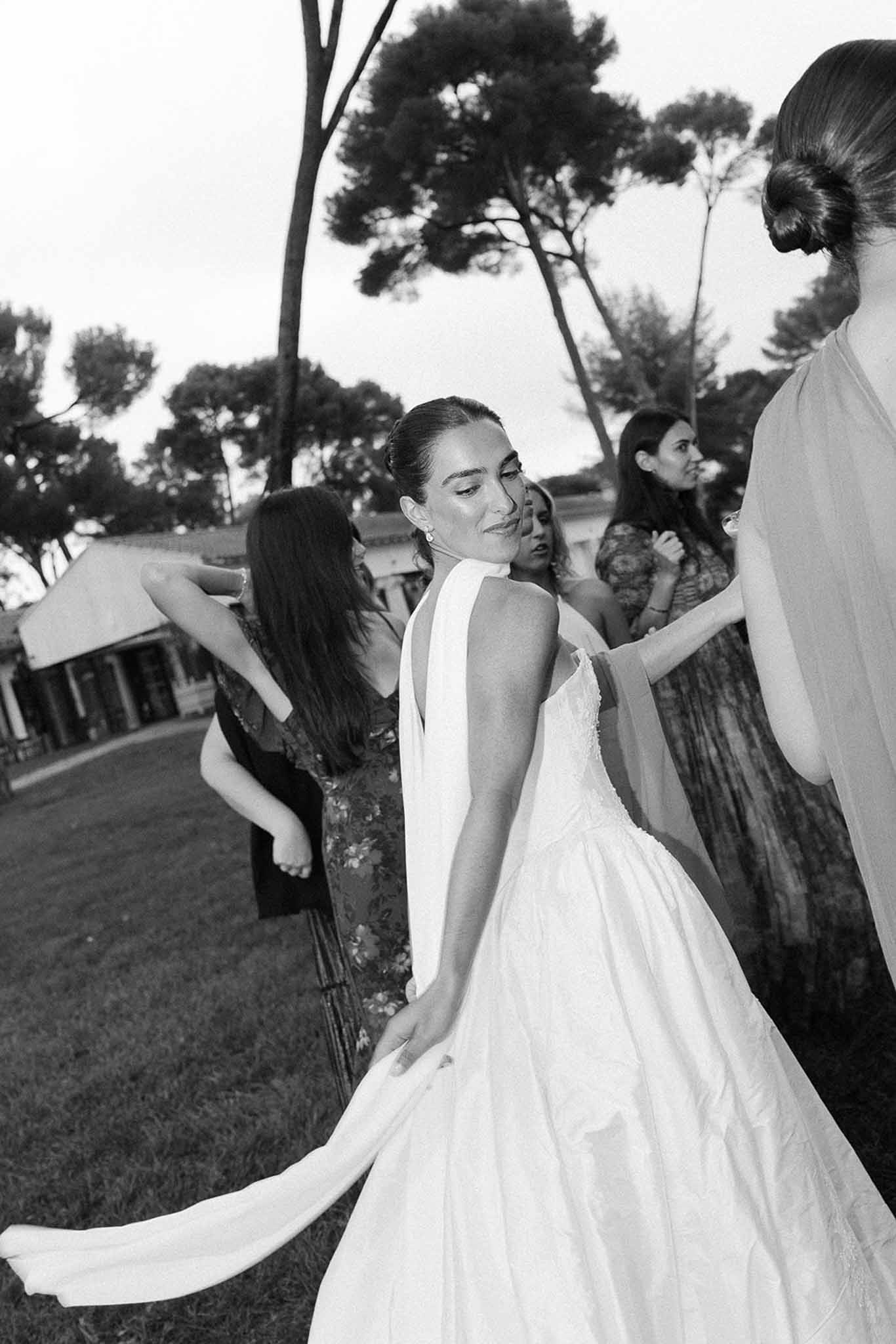 Bride with bridesmaids fluffing train on lawn at Domaine Rocabella, Cote d'Azur