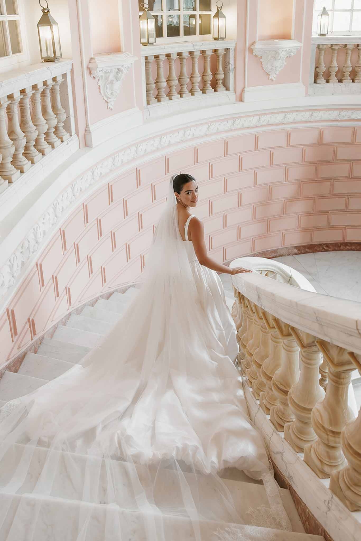 Bride descending pink staircase with long veil at Domaine Rocabella, Cote d'Azur